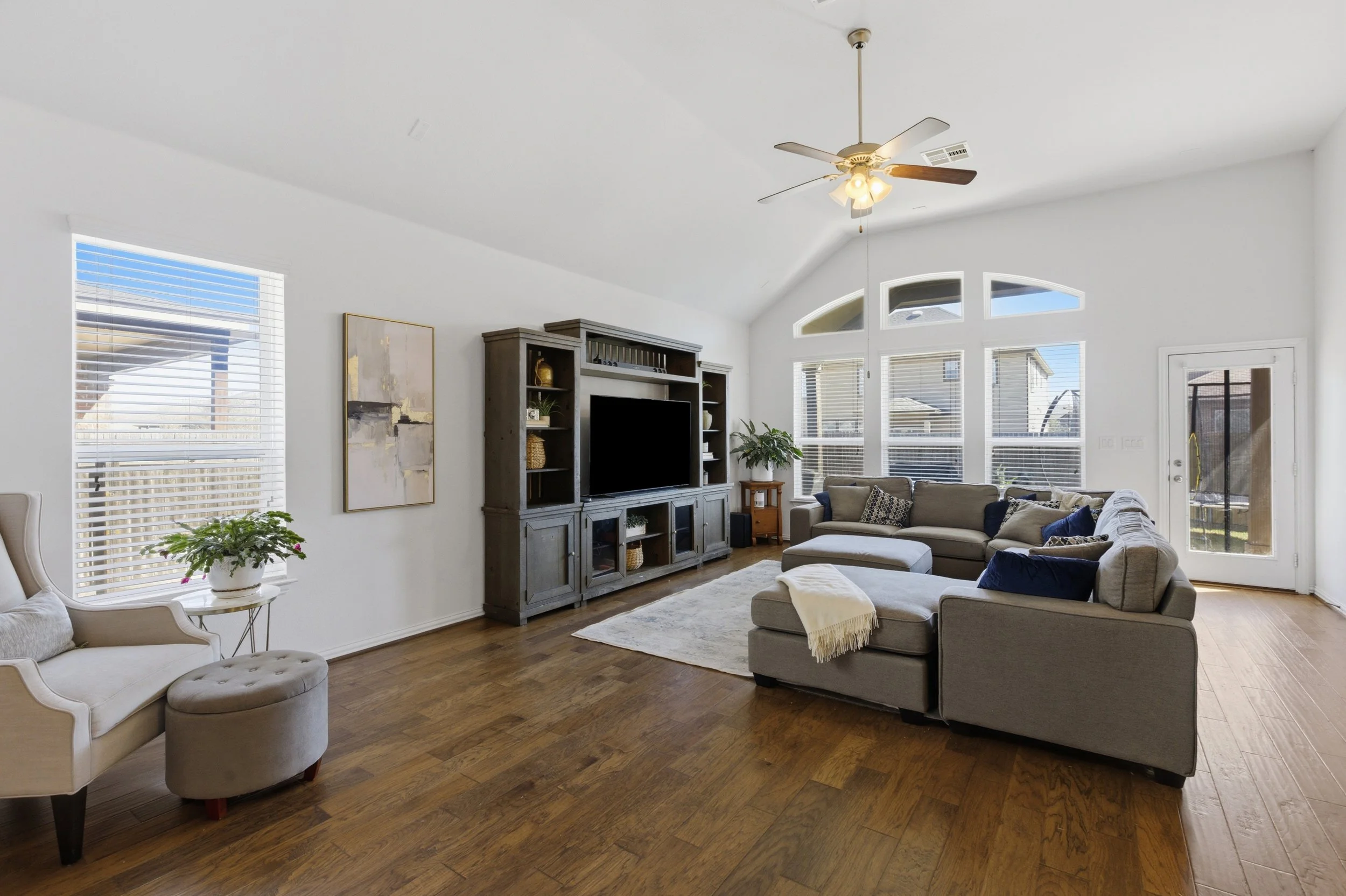 Open concept living room at 5386 Parma St Round Rock TX with large windows and natural light connecting to kitchen and dining areas.