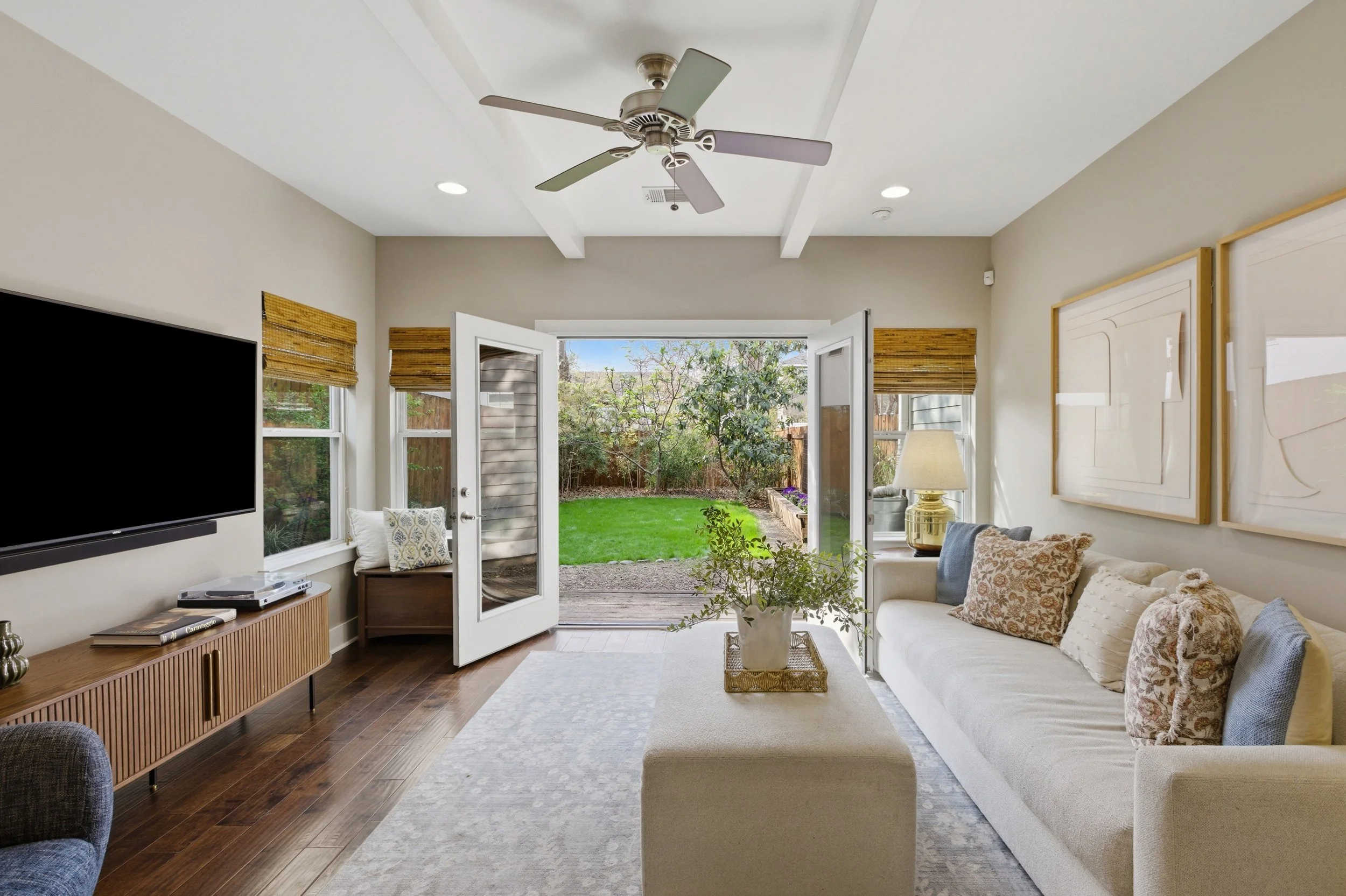 Bright open-concept living room in Brentwood Austin TX condo with large windows and French doors to backyard.