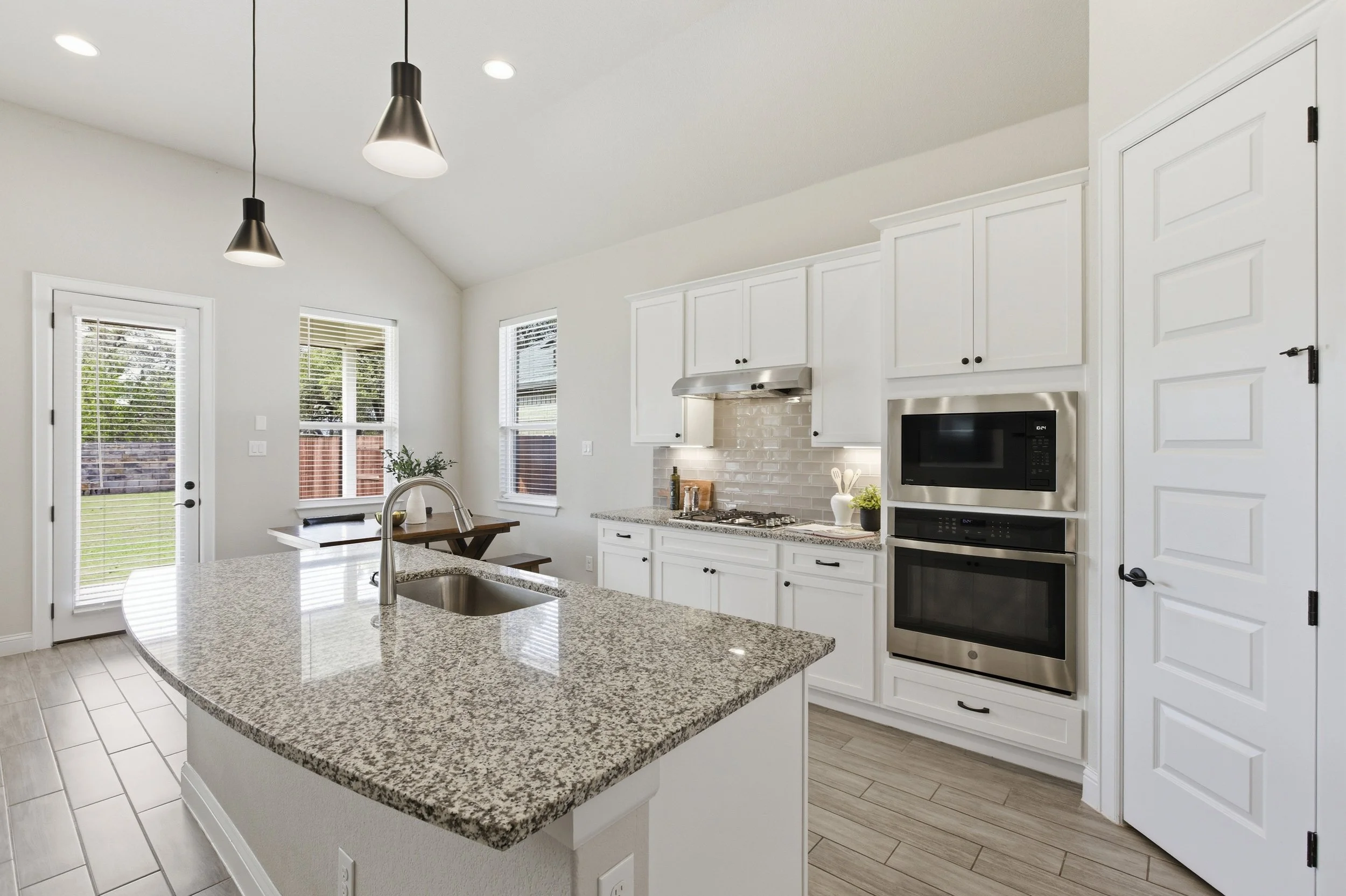 The kitchen features granite countertops, a large center island, built-in appliances, and a walk-in pantry | Georgetown, TX