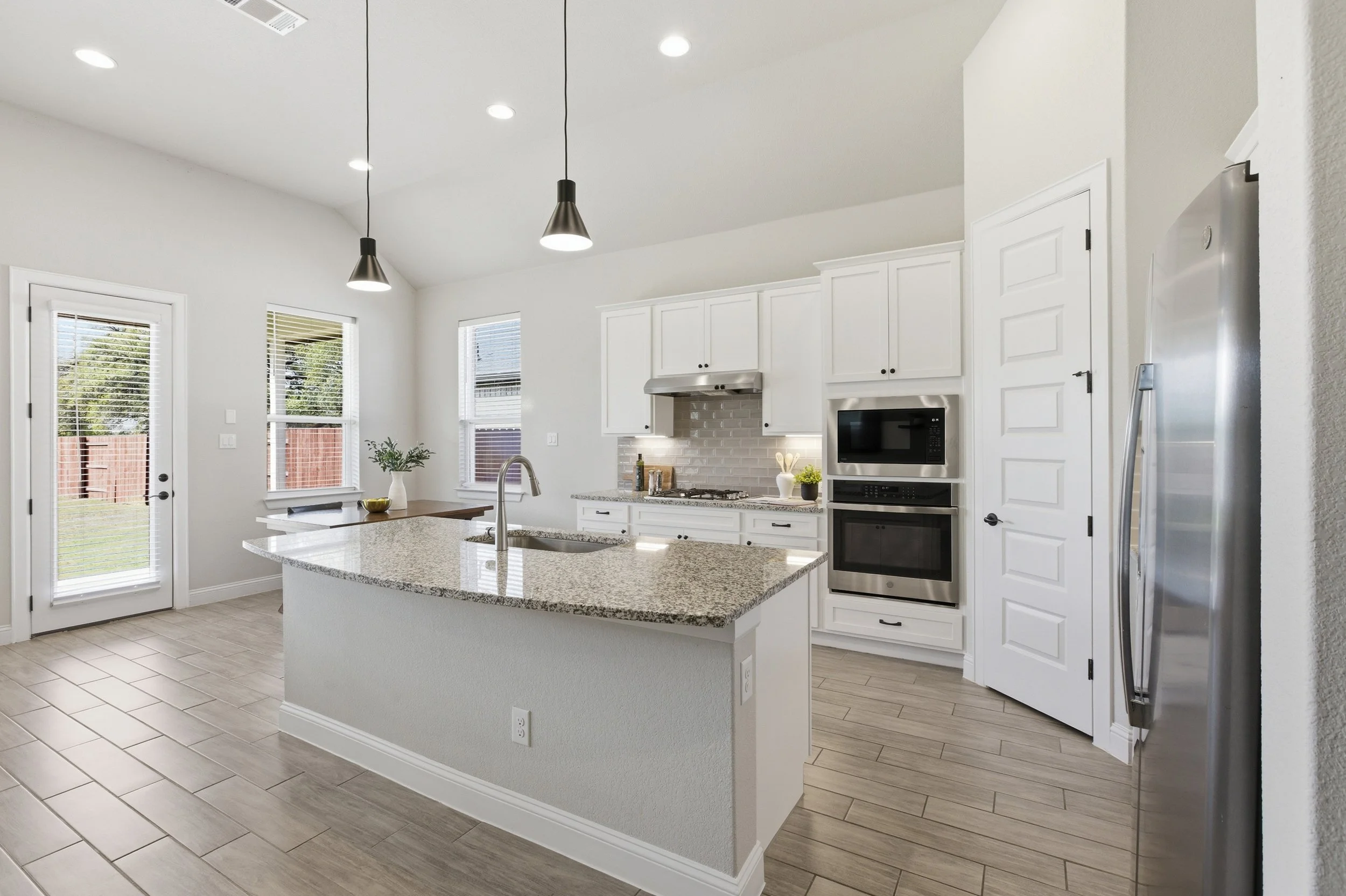 The kitchen features granite countertops, a large center island, built-in appliances, and a walk-in pantry | Georgetown, TX
