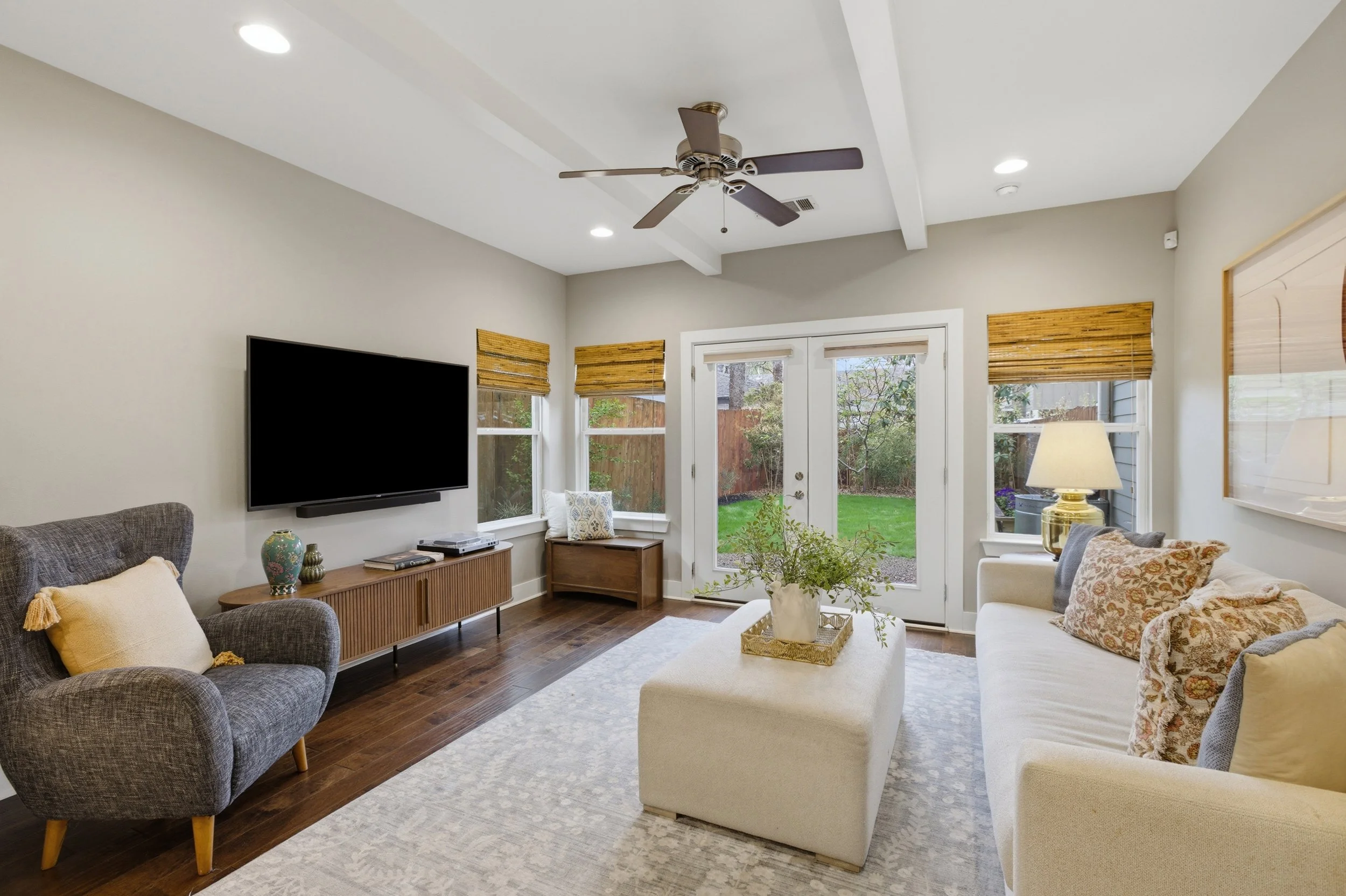 Bright open-concept living room in Brentwood Austin TX condo with large windows and French doors to backyard.