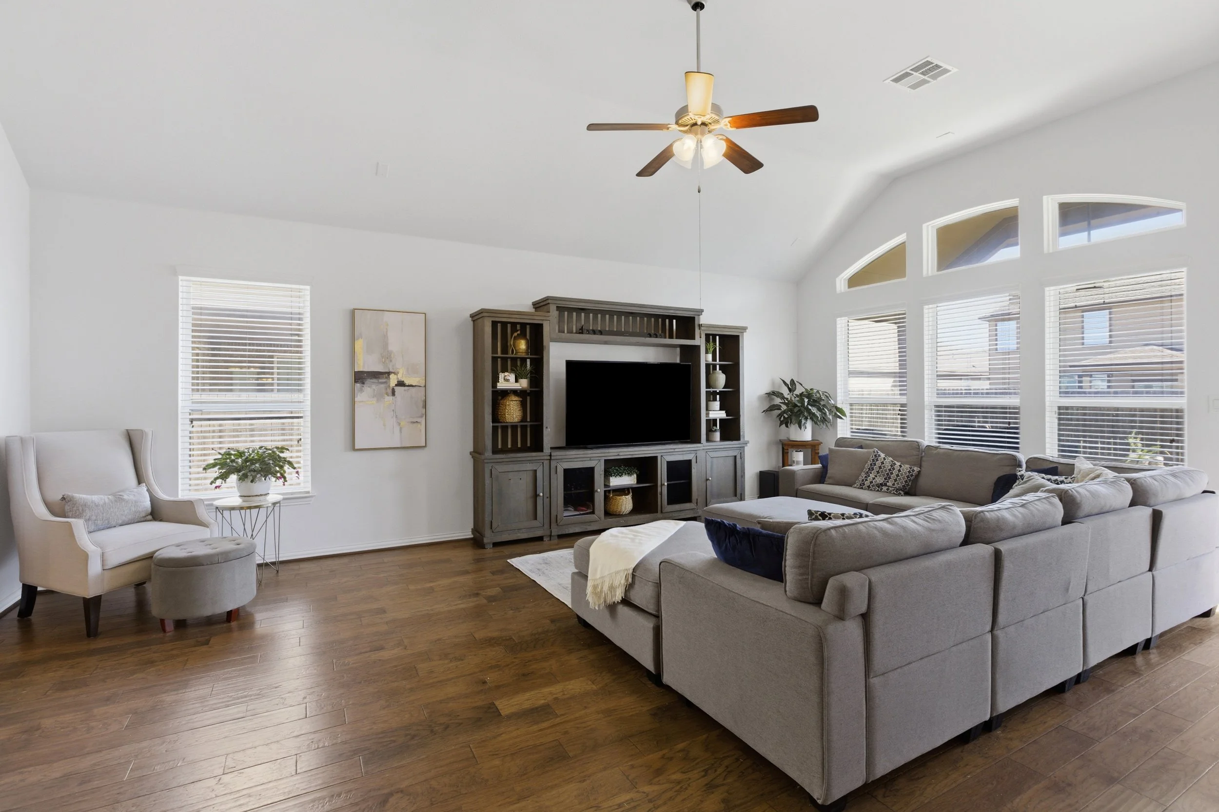Open concept living room at 5386 Parma St Round Rock TX with large windows and natural light connecting to kitchen and dining areas.