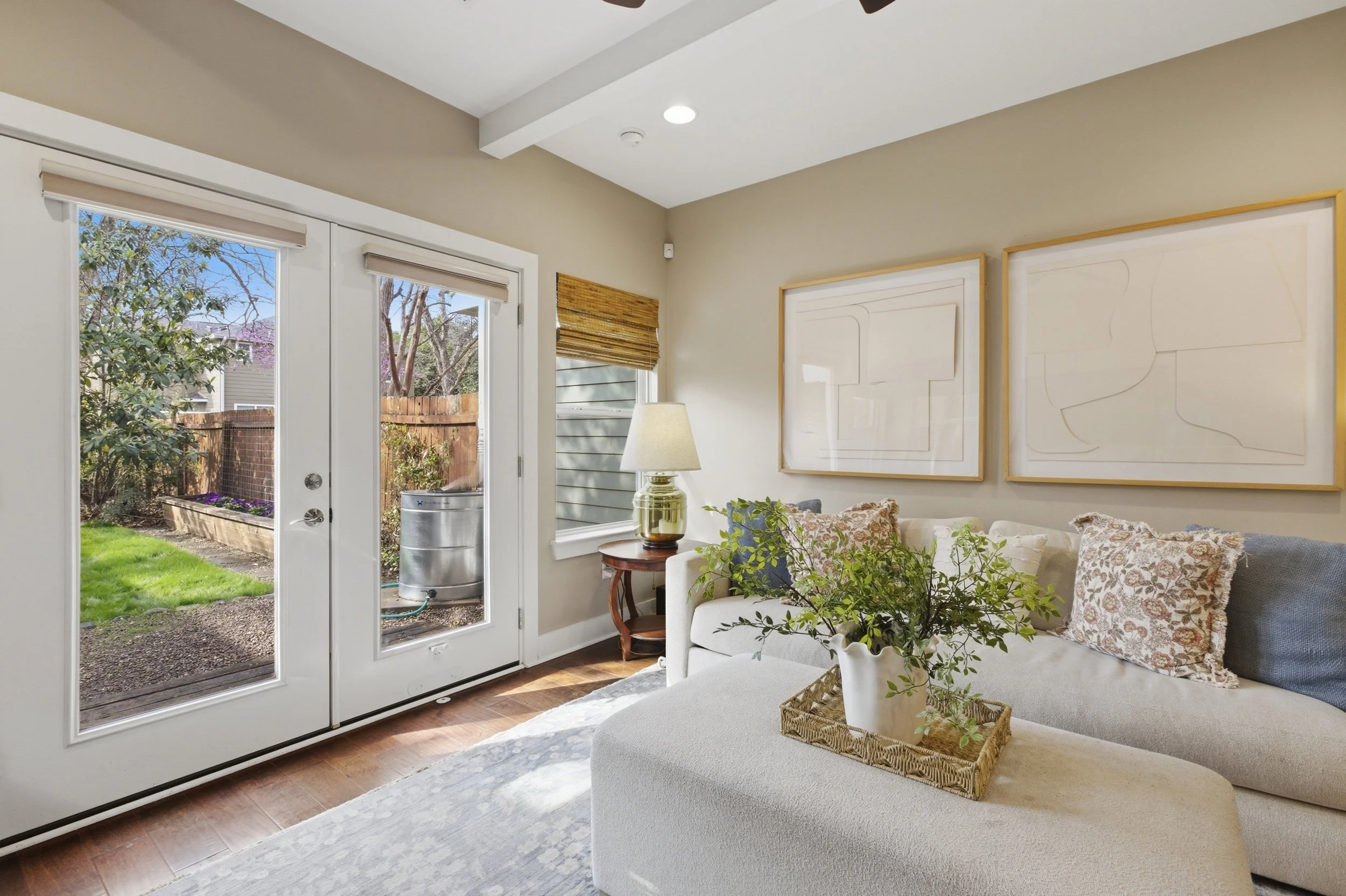 Bright open-concept living room in Brentwood Austin TX condo with large windows and French doors to backyard.