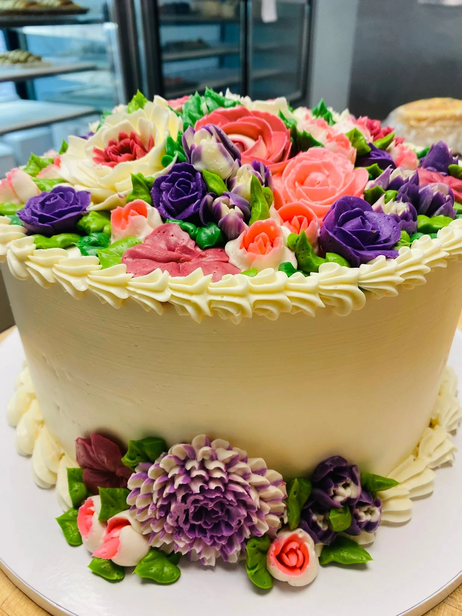 Custom cake topped with purple, pink and coral buttercream roses from The Bakery Waterford