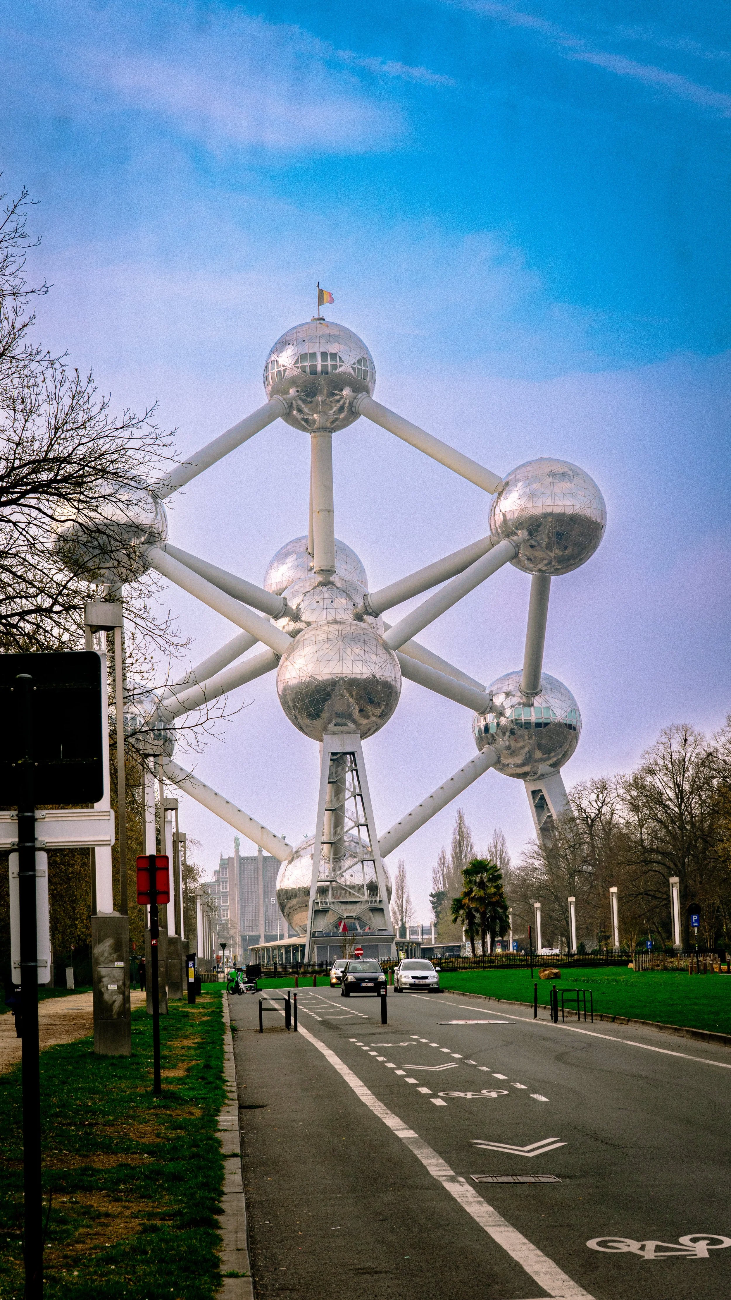 The Atomium, a monument in Brussels, Belgium, consisting of large metallic spheres connected by tubes, with a clear sky and some trees in the background.