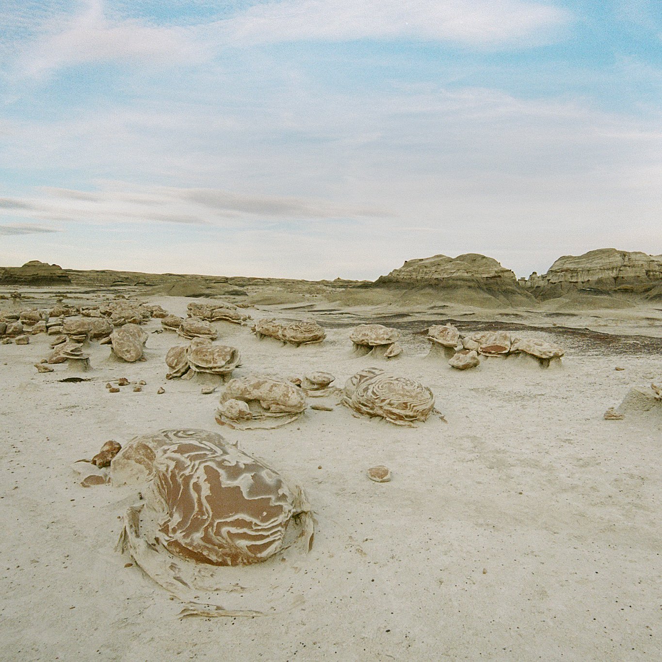 Desert landscape with layered rocks and a blue sky with some clouds.