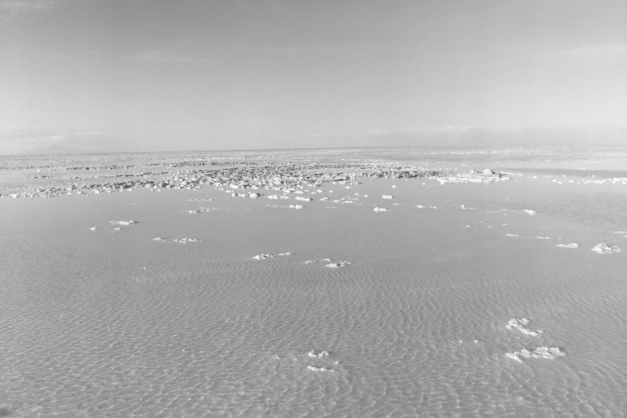 Snow-covered landscape with footprints leading into the distance, under a clear sky.