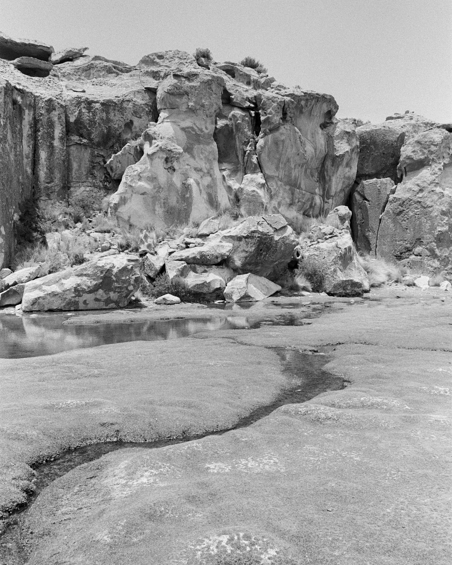 Black and white photo of a rocky landscape with large boulders and a small stream flowing over the rocks.