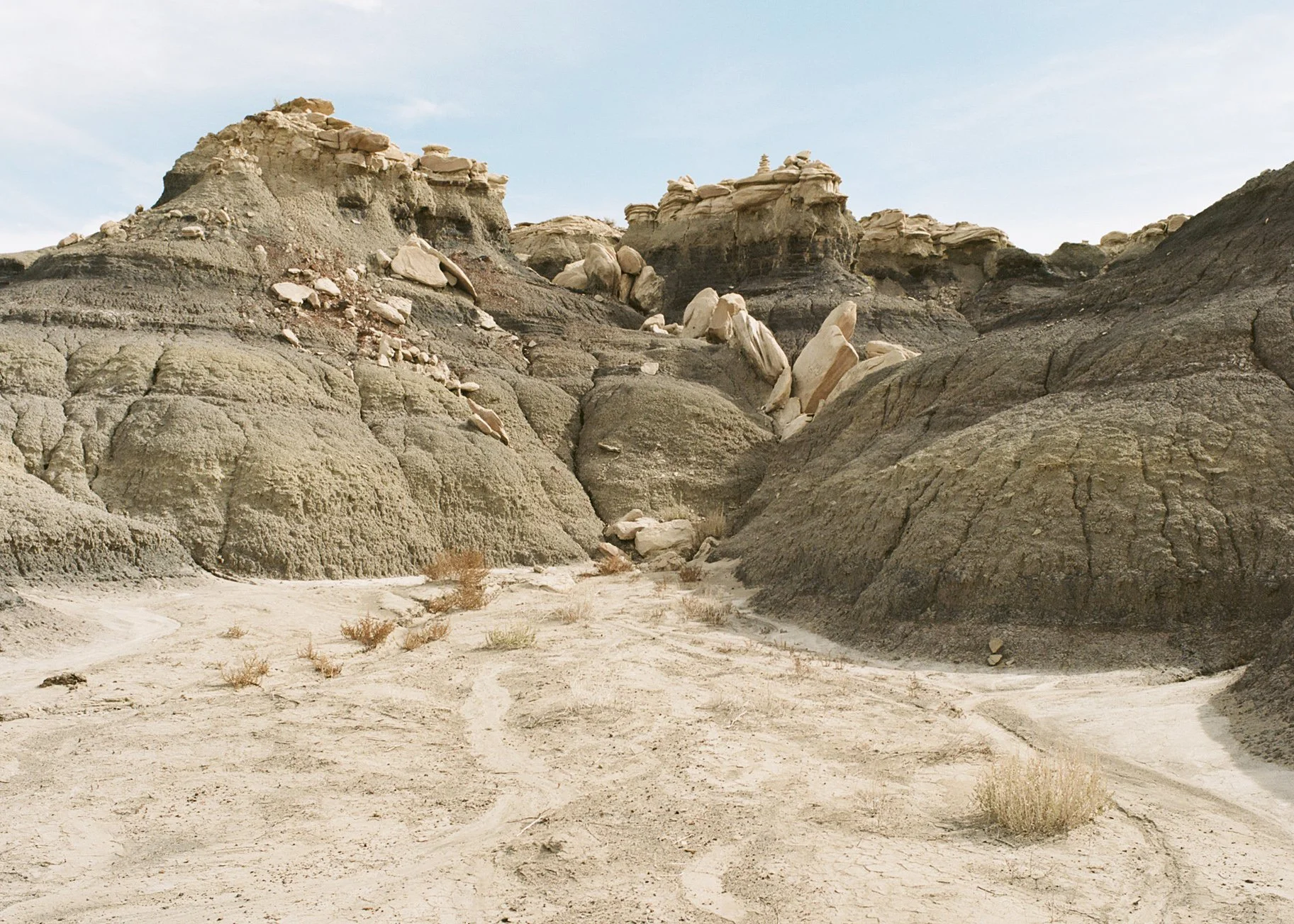 Desert landscape with large, eroded rocks and sandy ground under a partly cloudy sky.