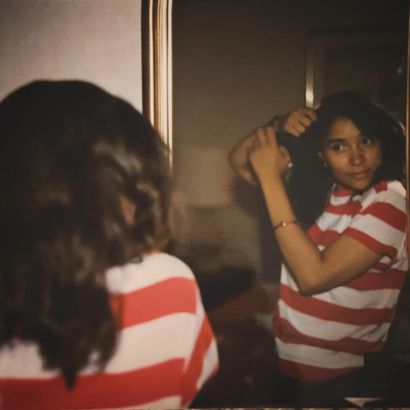 woman doing her hair in the mirror