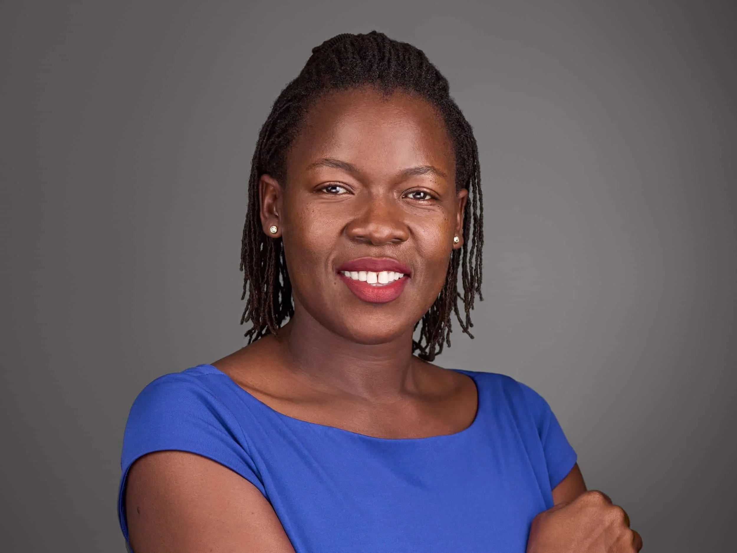 Headshot of a woman with dark skin and dreadlocks, wearing a blue top and smiling at the camera | Headshot & Branding Photography | Washington, DC 