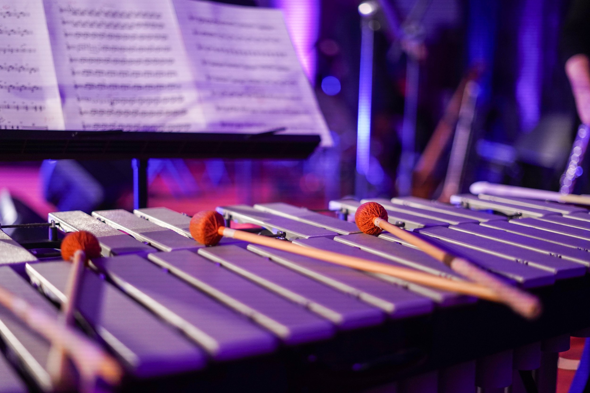 Close-up of a vibraphone with mallets and sheet music, in a dimly lit music venue.