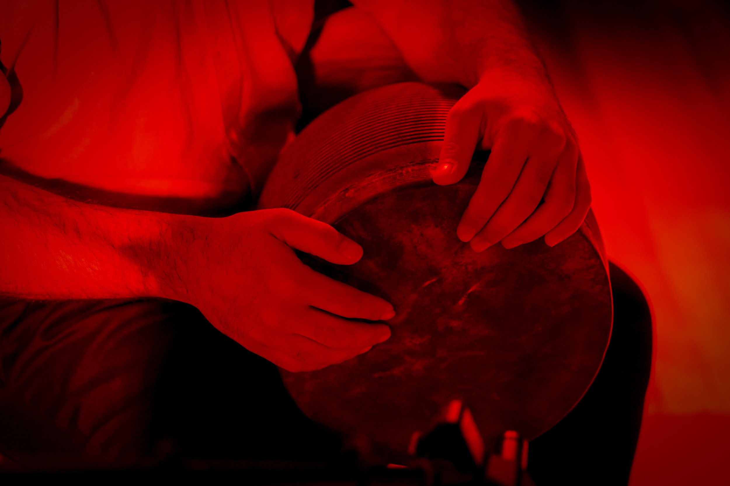Person playing a drum in red lighting