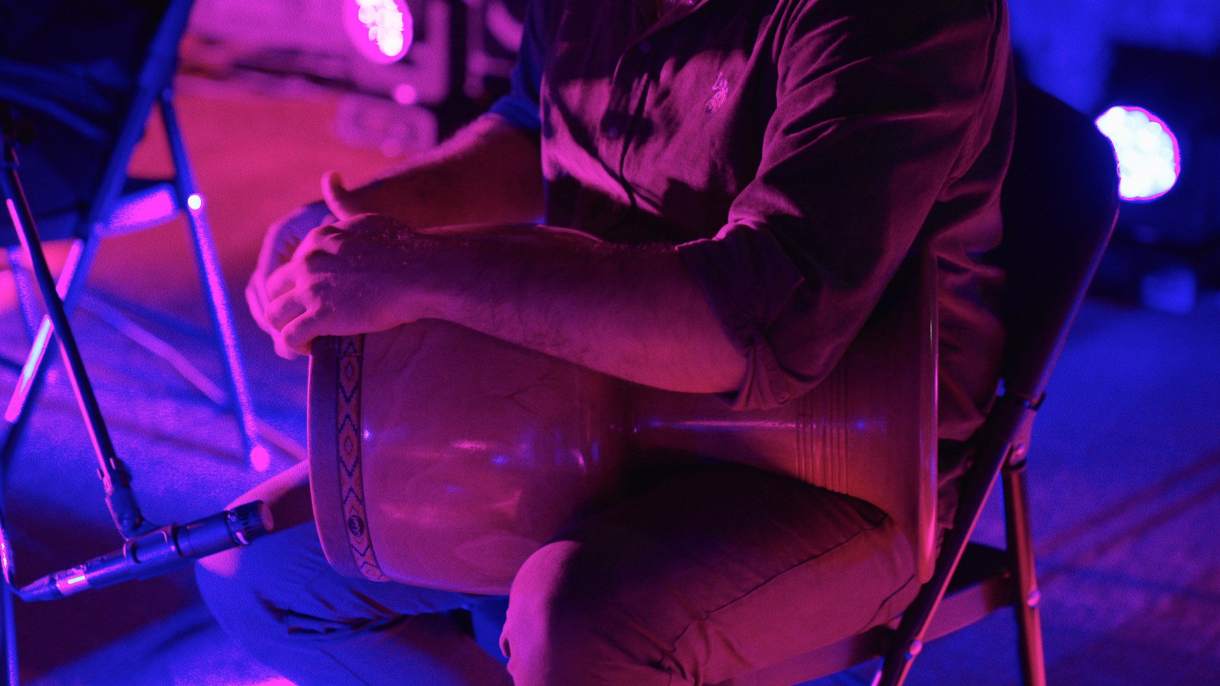 Person playing a traditional drum in purple lighting