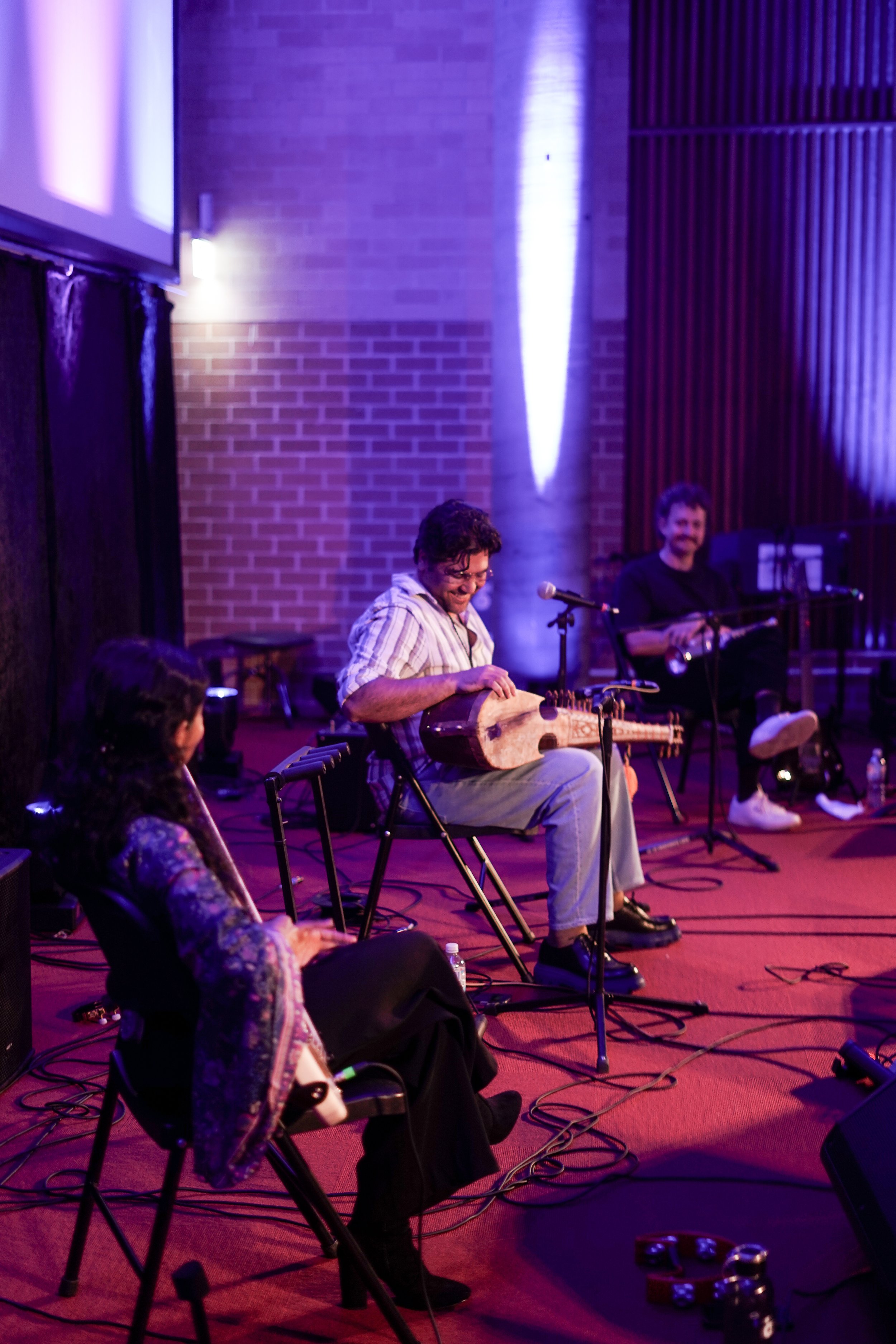 Musicians performing on stage with string and wind instruments.