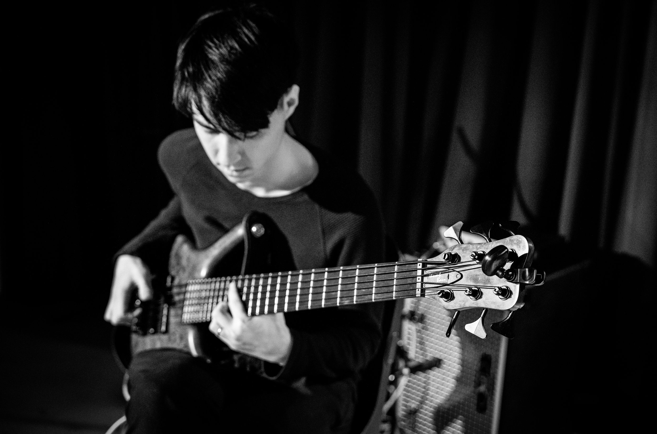 Black and white photo of a person playing an electric bass guitar.