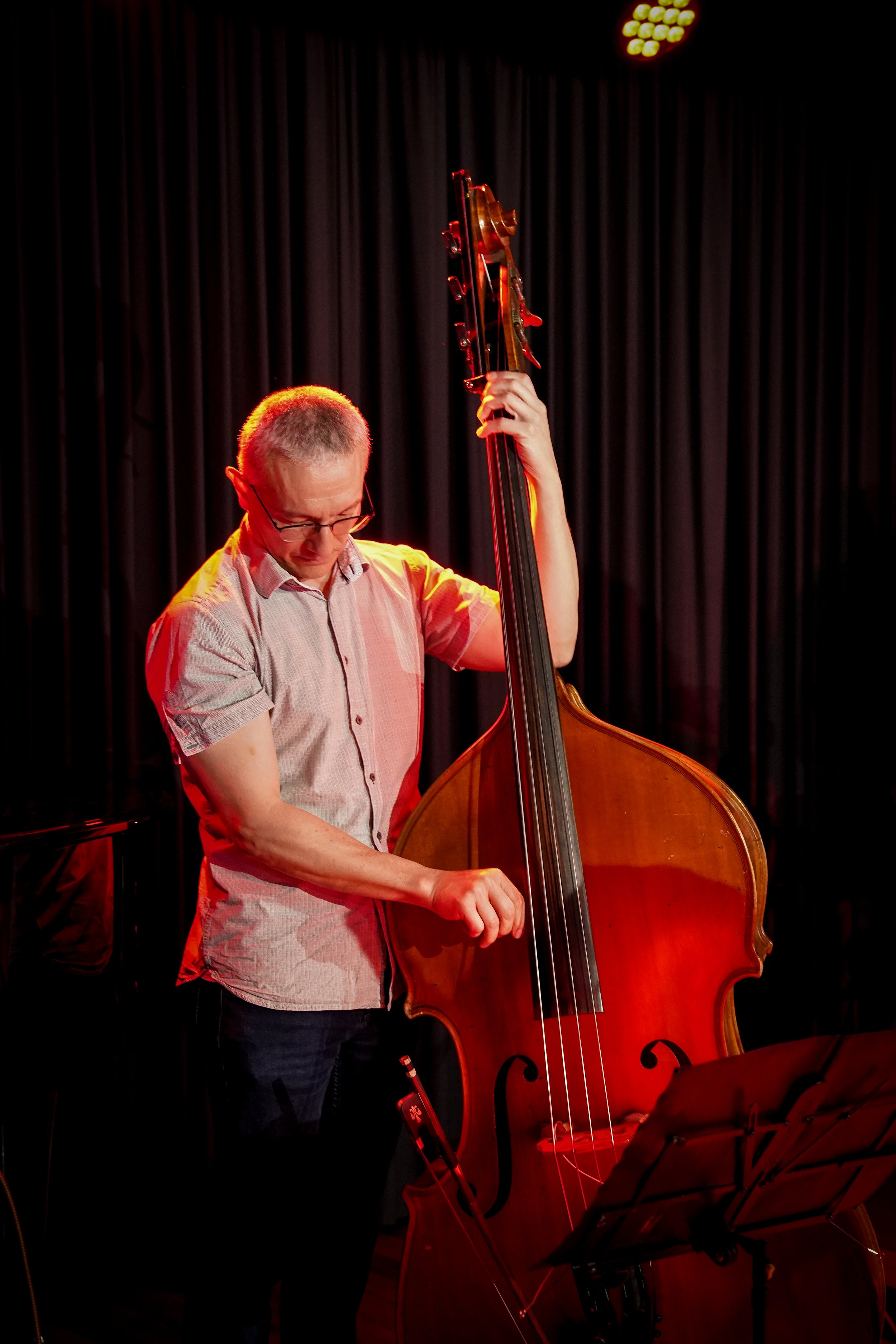 Musician playing a double bass on stage with red lighting