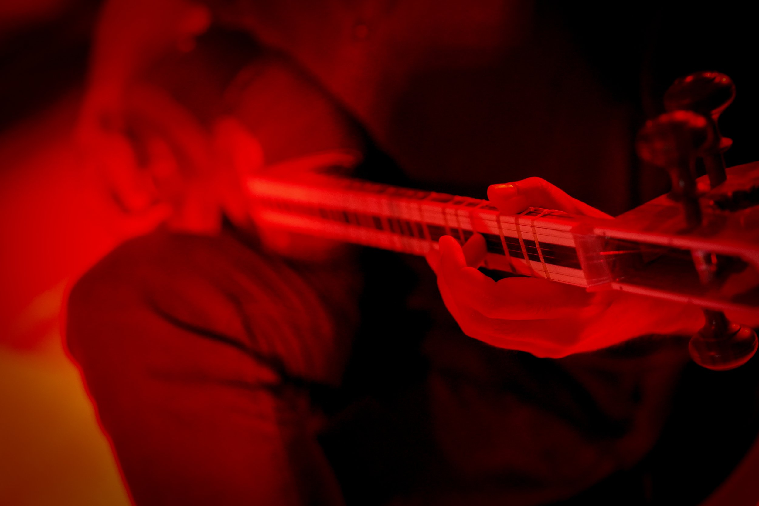 Person playing a string instrument under red lighting