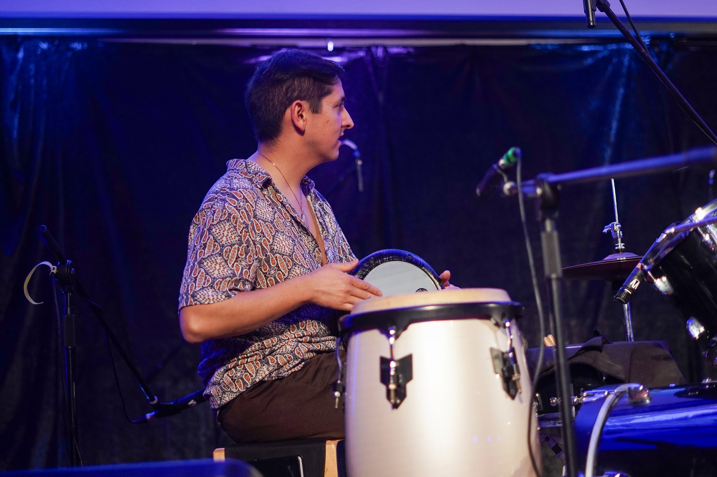 Musician playing percussion instruments on stage with conga and doumbek