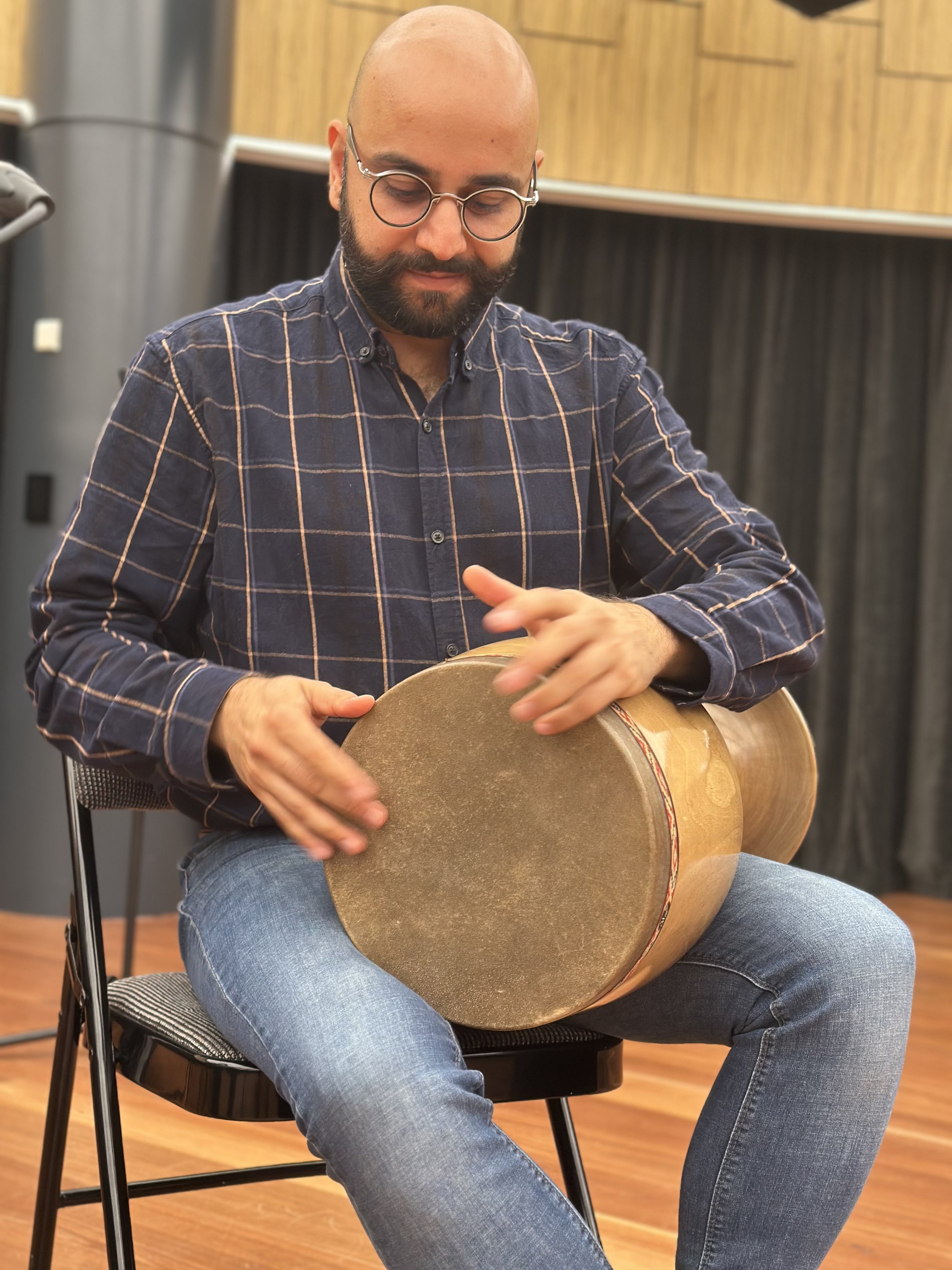 Person playing a goblet drum indoors
