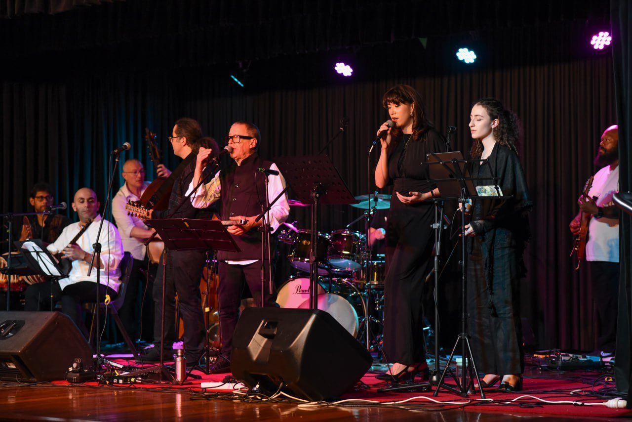 Musicians and singers performing on stage with various instruments.