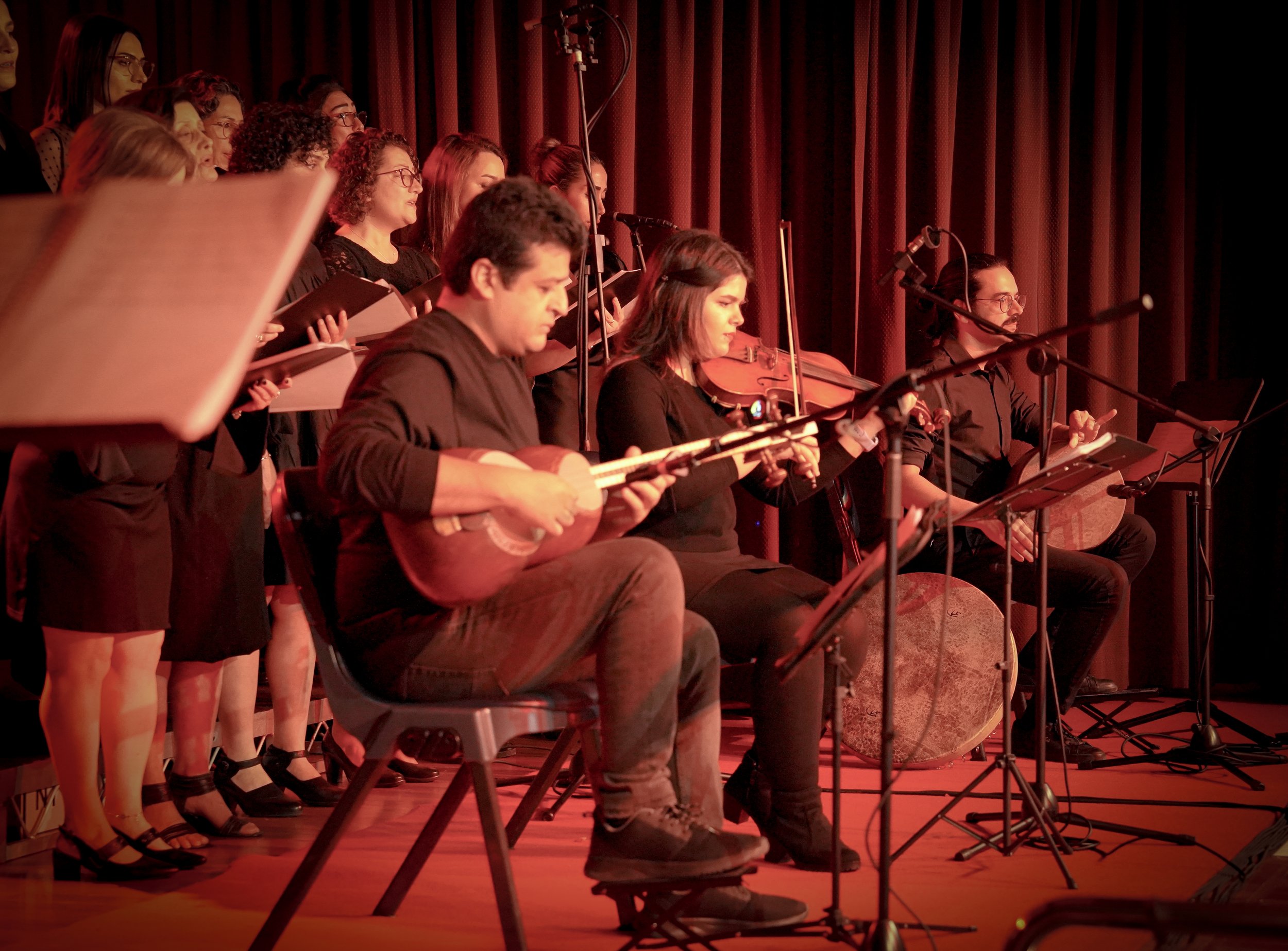 Musical performance with choir and musicians playing string and percussion instruments on stage.