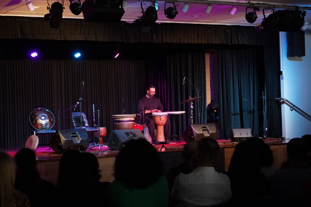 Musician on stage with drums and microphone, audience watching
