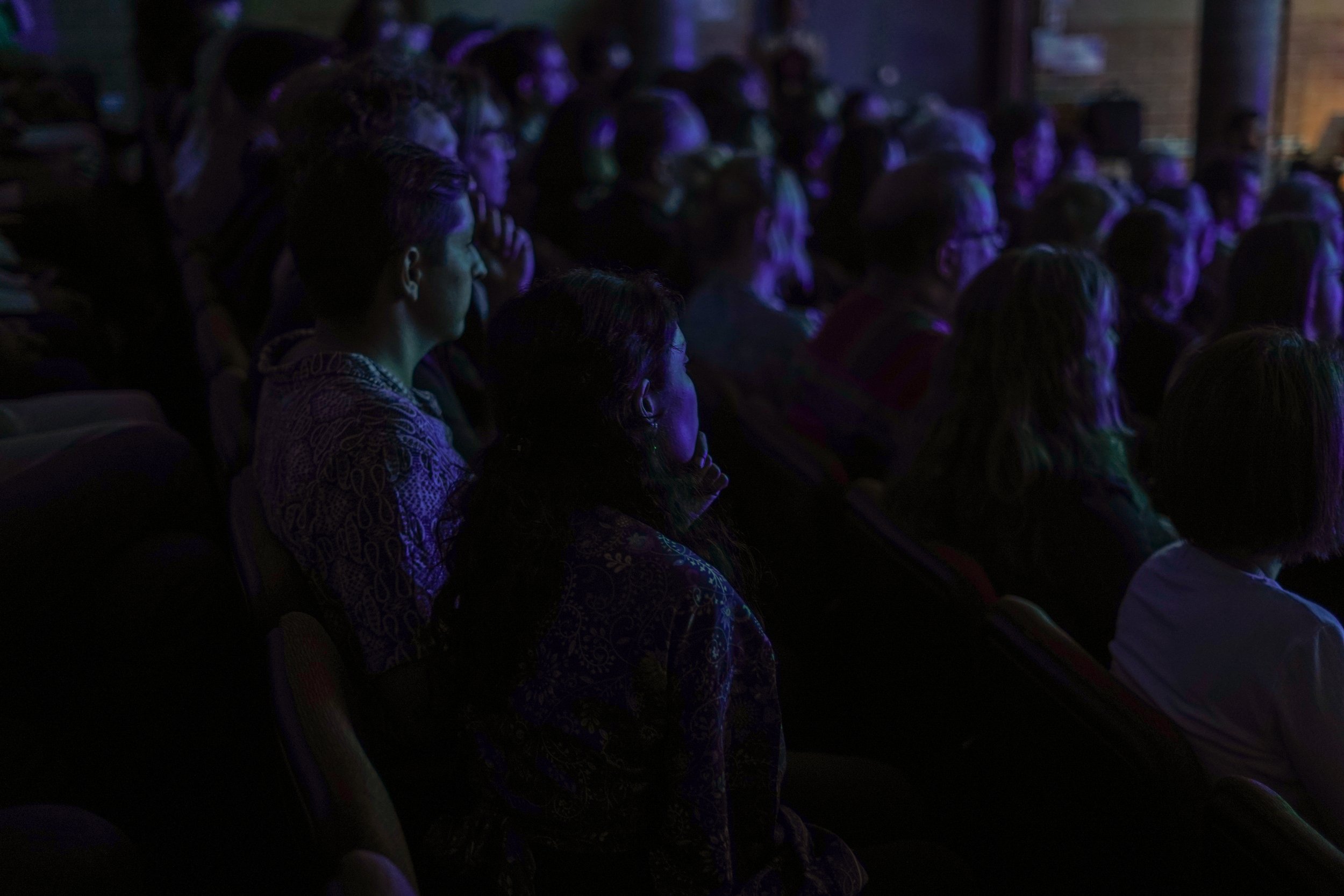 Audience watching a performance, dimly lit theater