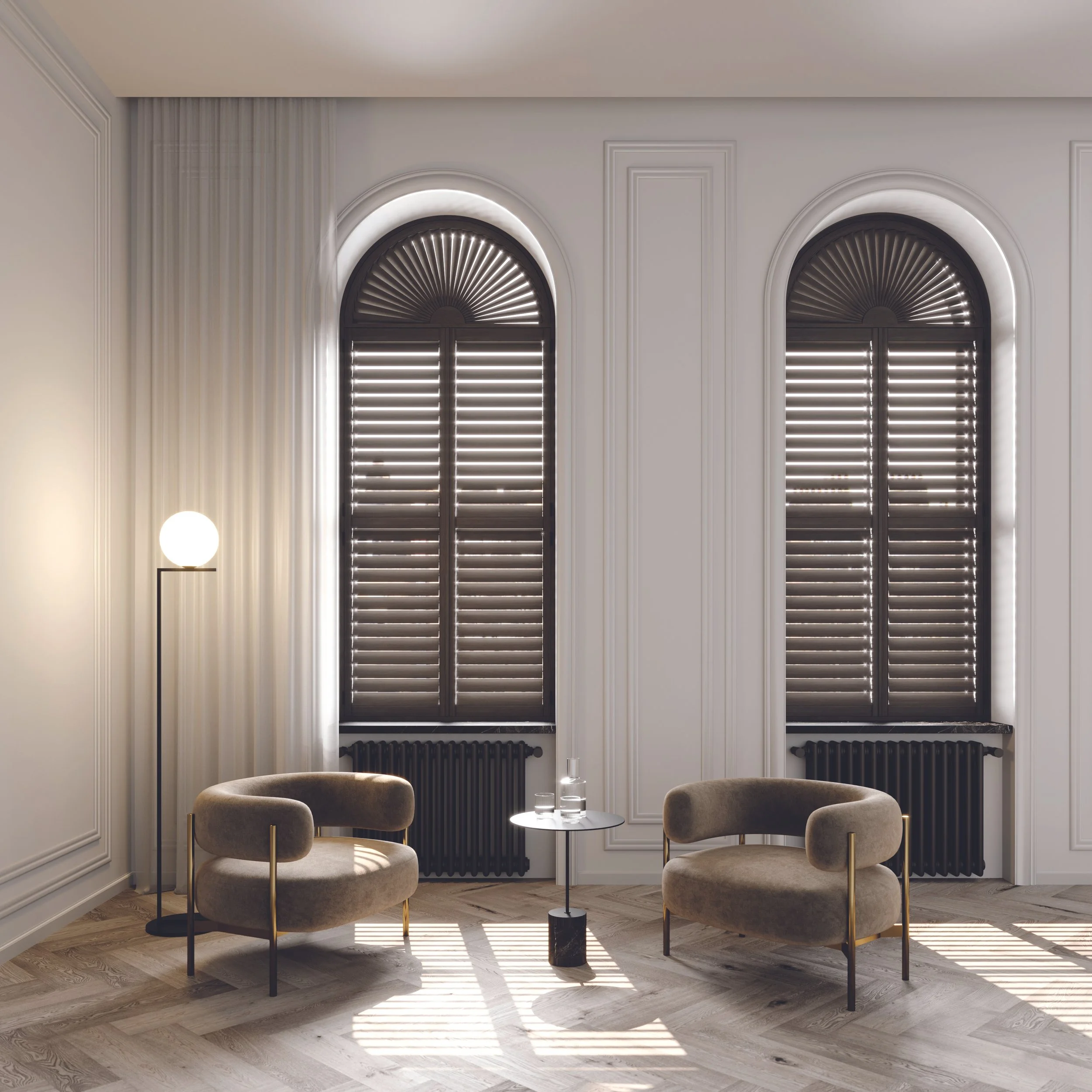 Modern living room with two large arched windows with dark blinds, two beige armchairs, a small round table, a black radiator, and a tall floor lamp with a white globe shade, sunlight casting shadows on the wooden floor.
