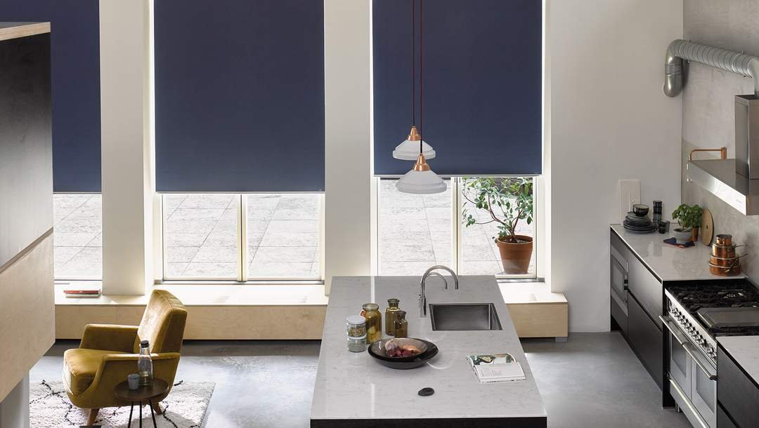 Modern kitchen with an island, black cabinetry, pendant lights, and large windows with purple roller blinds.