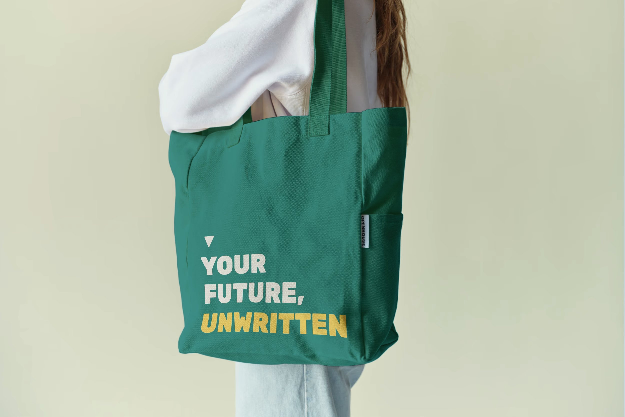 Branded Tote bag in teal being carried by a person wearing light jeans and a white jumper