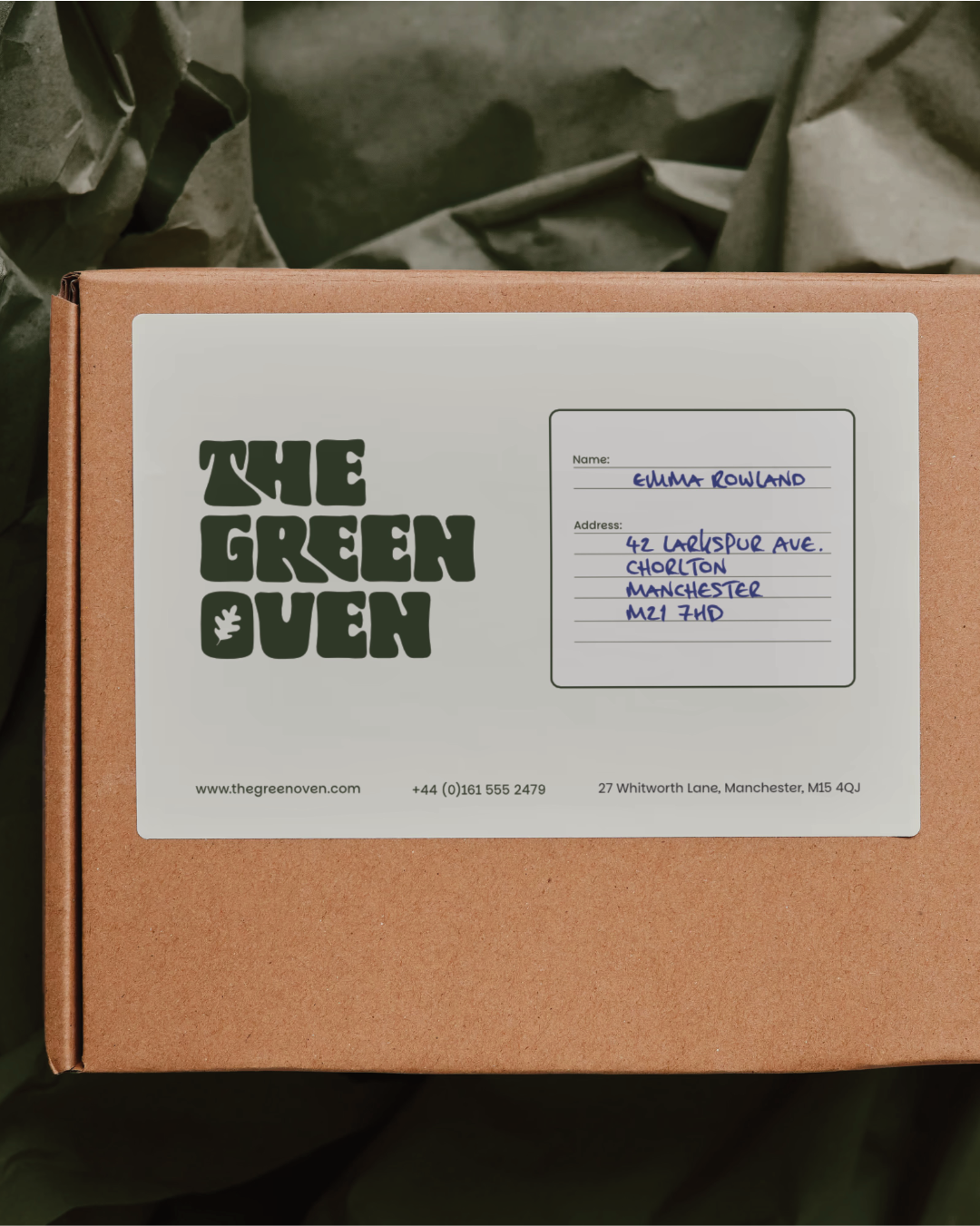 Brown mailer box with a branded delivery label showing The Green Oven Logo and contact details