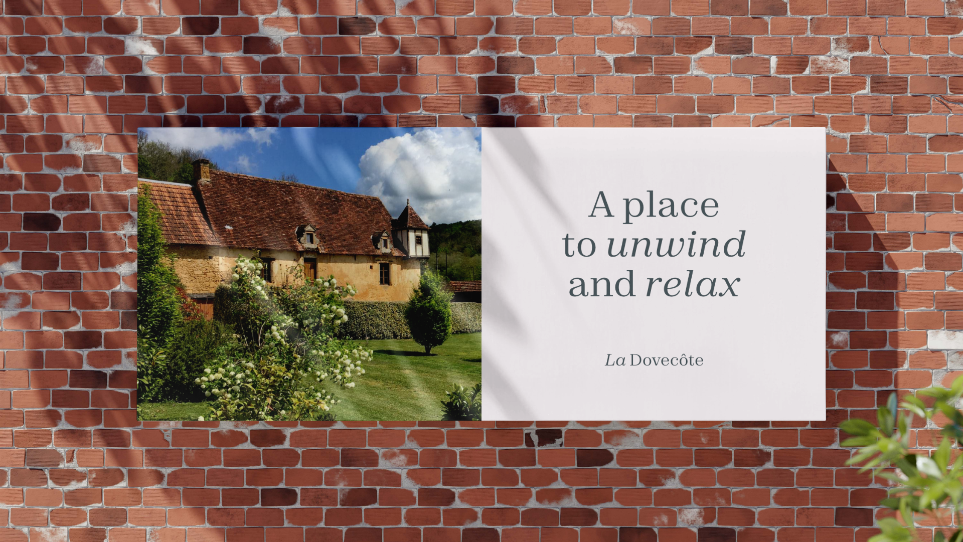A scenic image of an old rustic house with a red tile roof, surrounded by lush green gardens and trees, under a partly cloudy sky with bright sunlight. Next to the house, there is a white wall with text that reads, 'A place to unwind and relax' and '