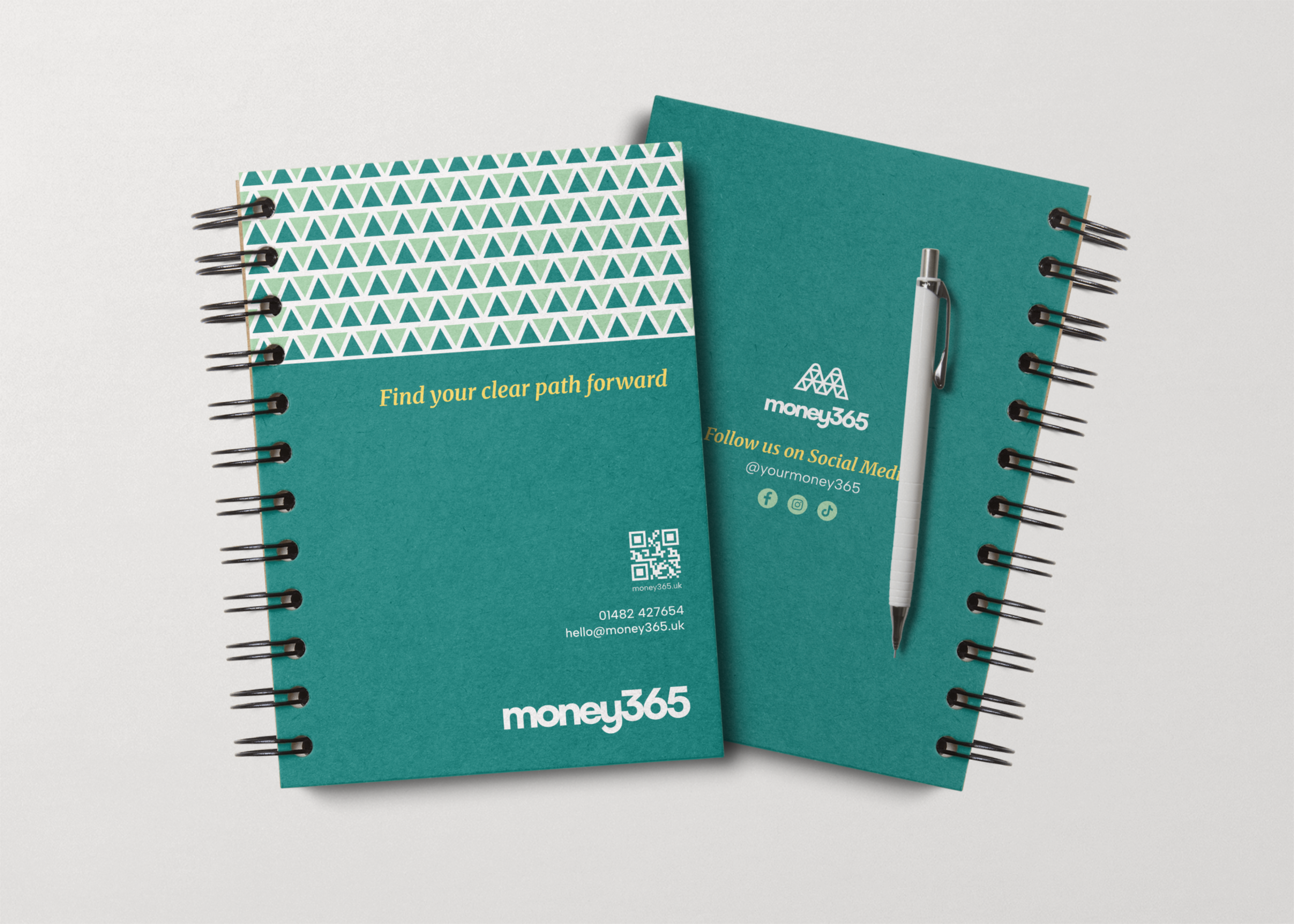 Money365 notebook showing front and back cover designs with a white pen