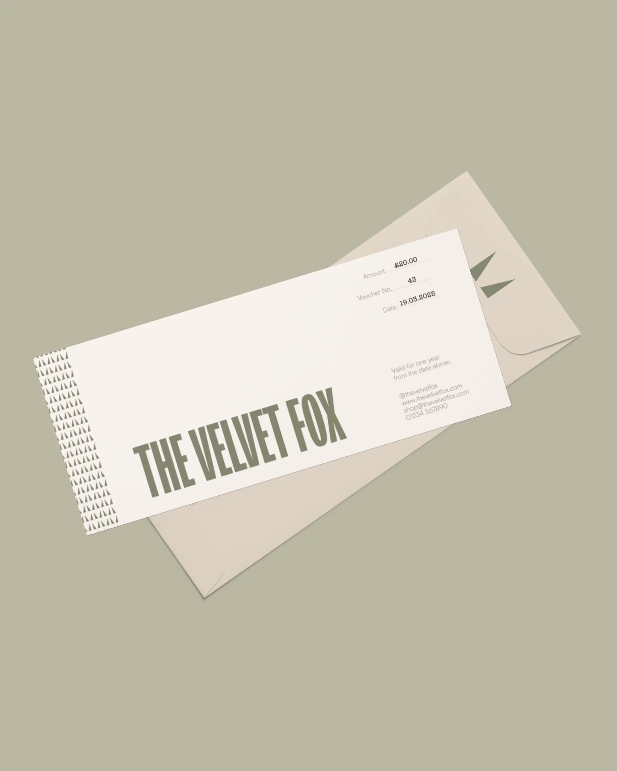 A gift card for THE VELVET FOX placed on a beige envelope on a green surface.