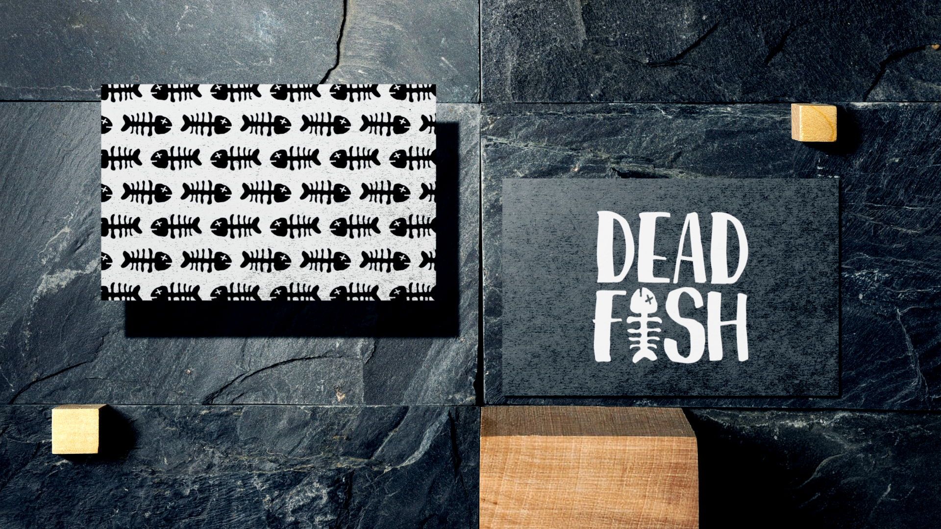Set of two black tiles with fishbone patterns and text, arranged on a dark stone surface with small wooden blocks