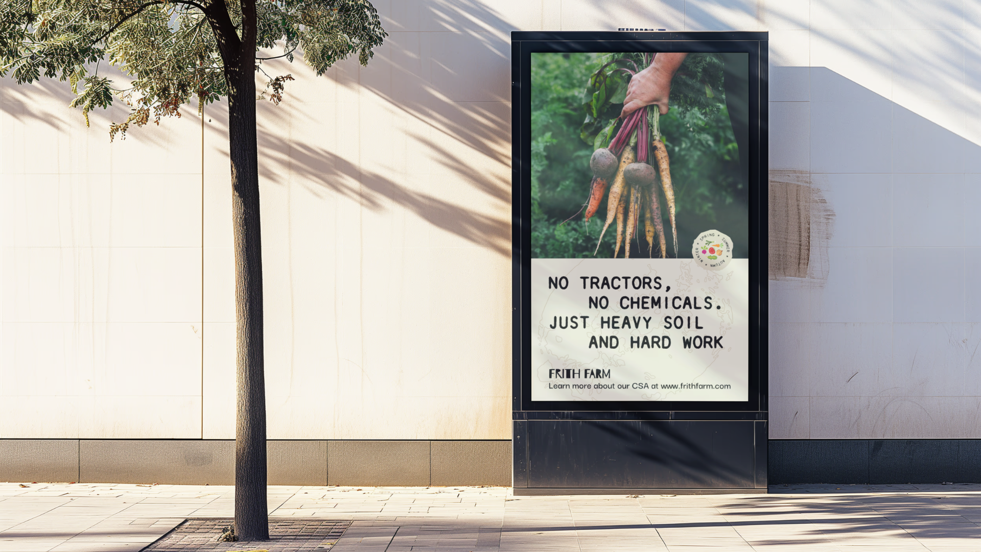 A tree casting shadows next to a digital billboard advertising organic carrots, with text: 'No tractors, no chemicals. Just heavy soil and hard work' and a website link.