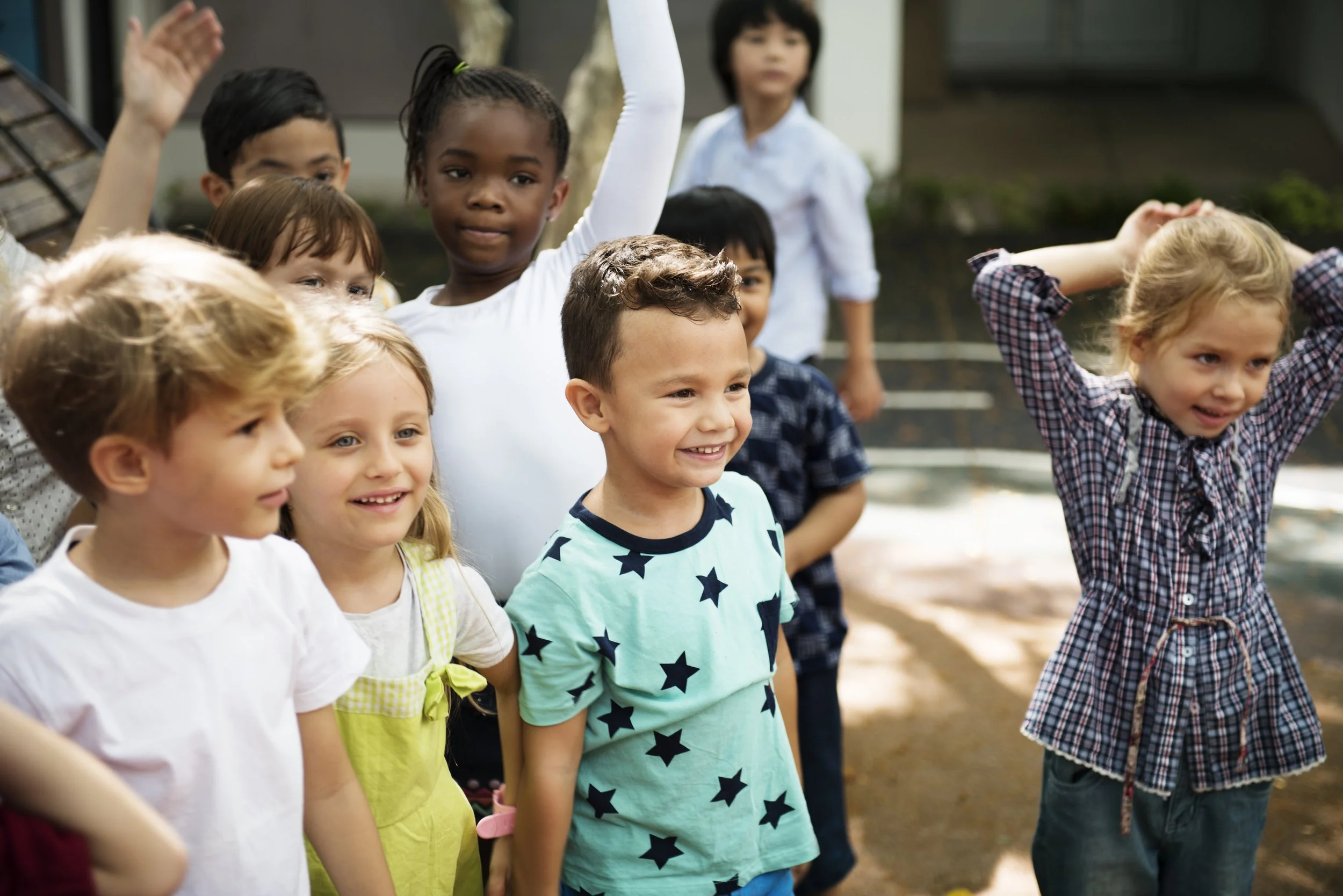 Group of diverse young children smiling and standing outdoors.