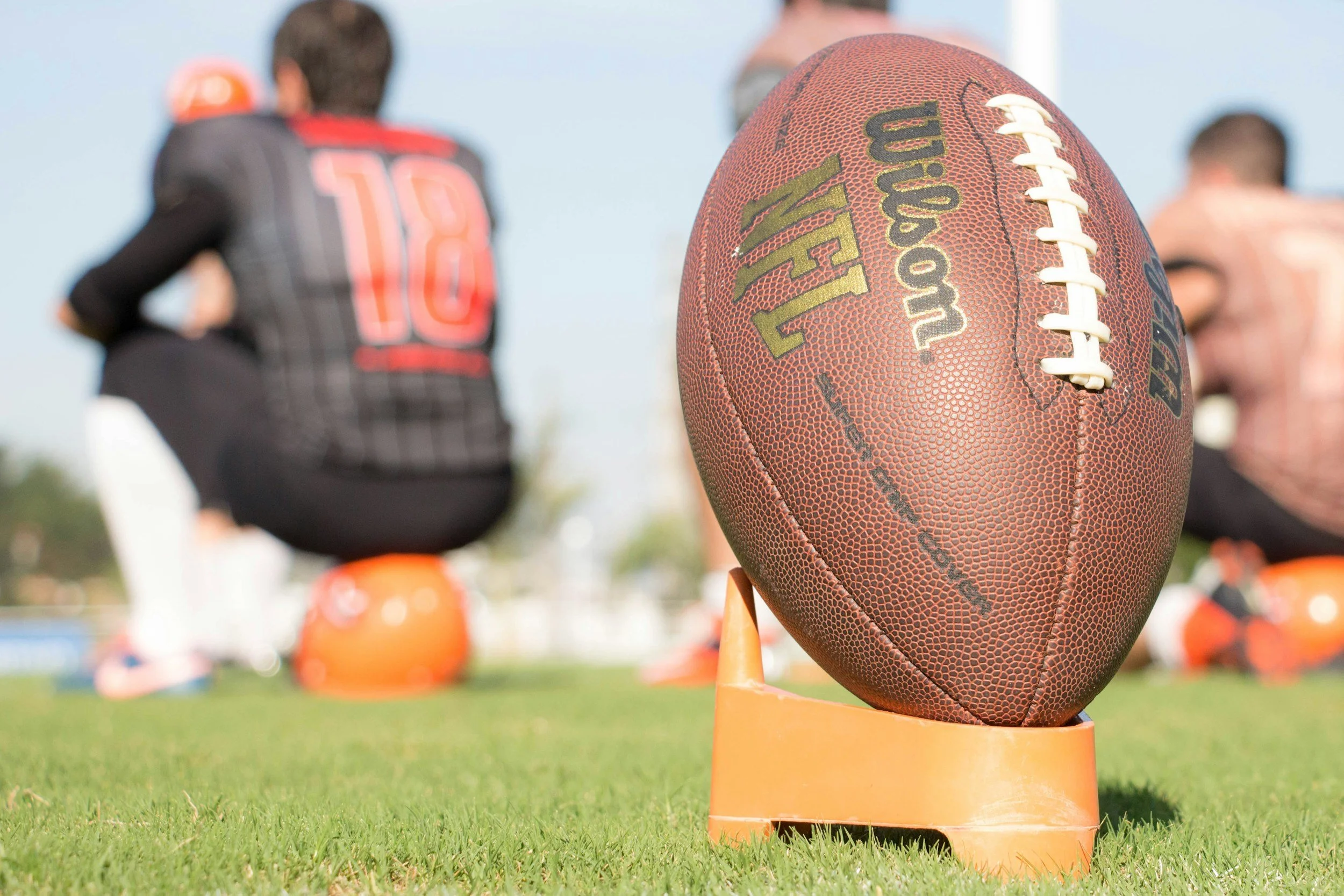 Football on tee with players in background
