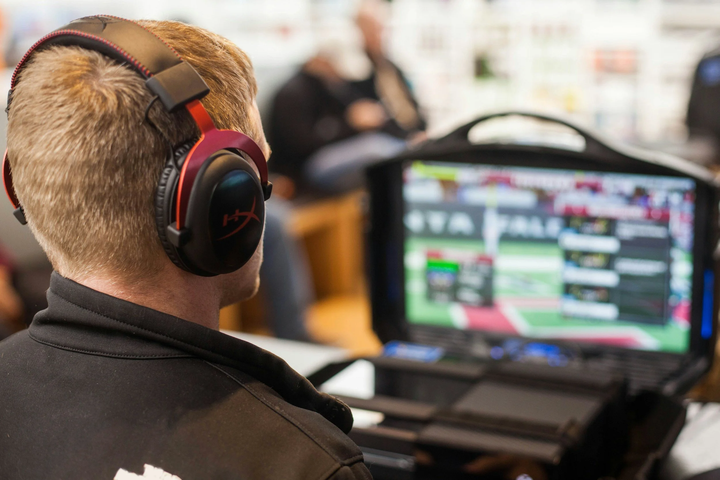 Person participating in a fantasy football draft on laptop wearing HyperX headphones