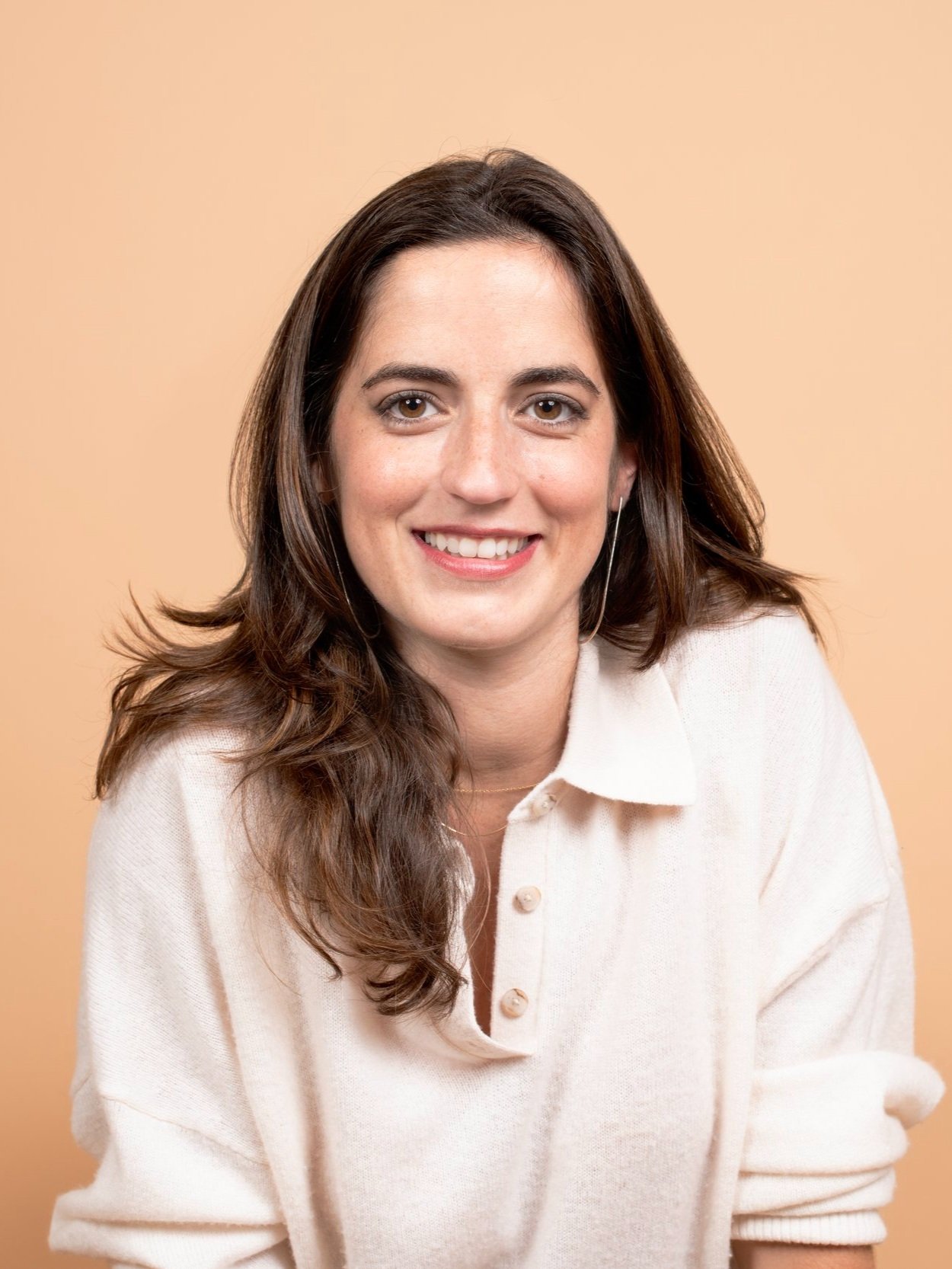 Woman smiling in front of a peach-colored background