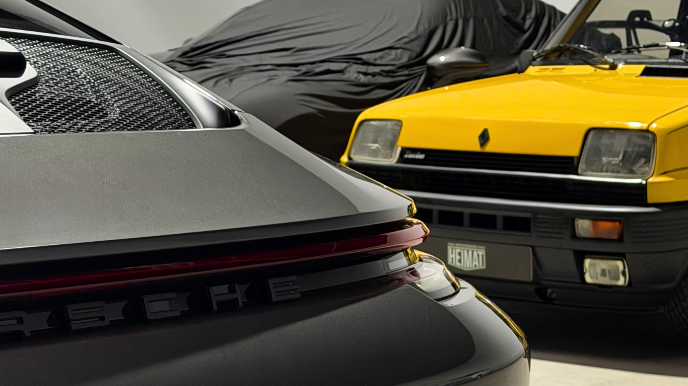 Zwei Autos, ein grauer Porsche und ein gelber Renault, stehen in einer Garage.