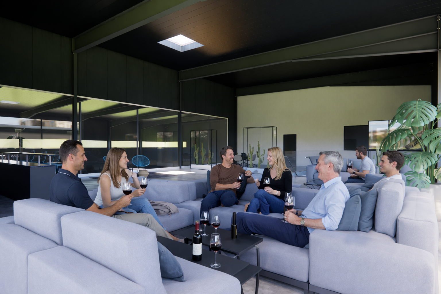 Ein paar Leute sitzen auf einem modernen Sofa und trinken Wein in einer Lounge mit viel natürlichem Licht und Pflanzen.
