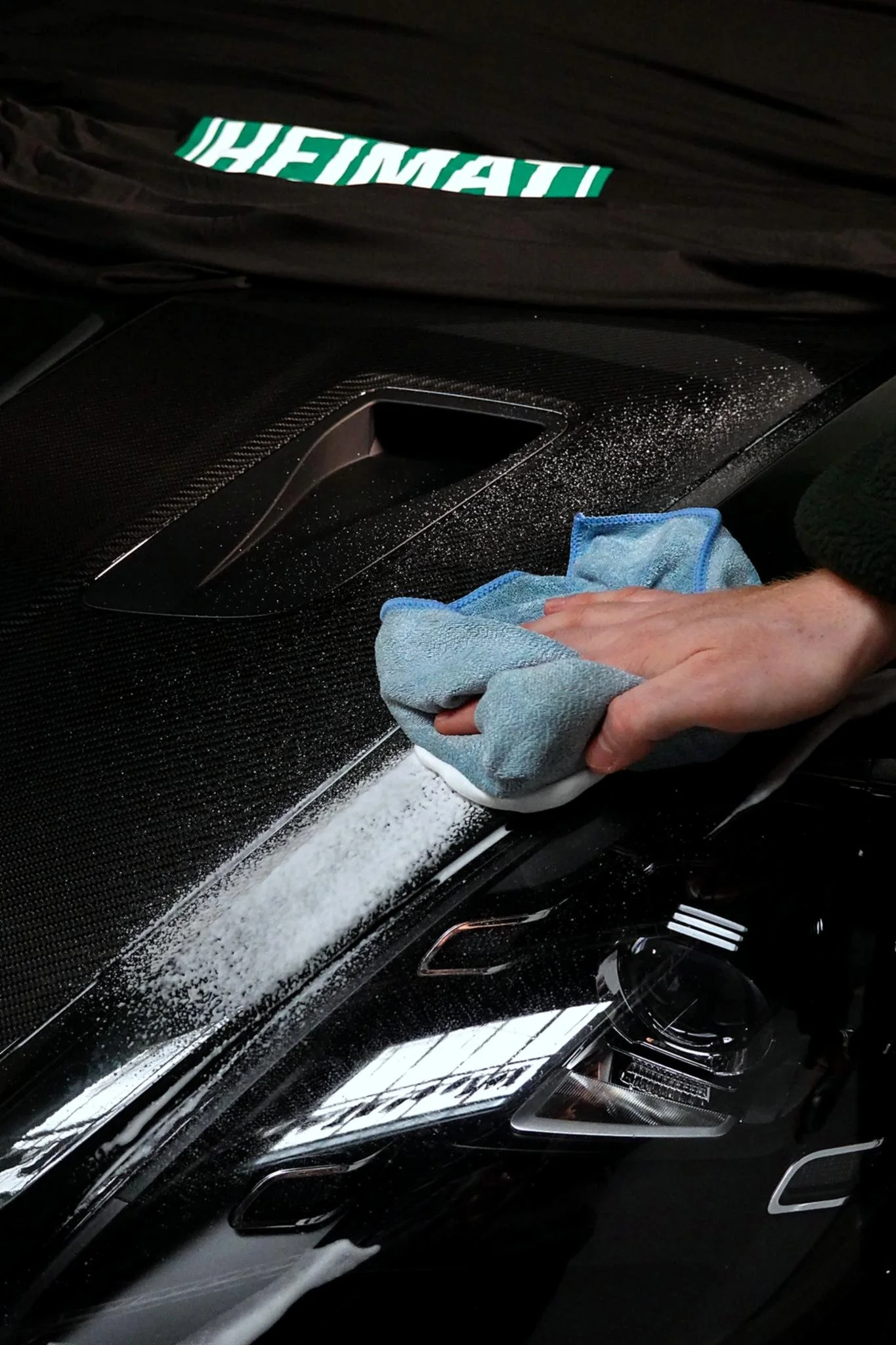 Nahaufnahme, wie eine Hand mit einem Tuch ein Auto abwischt.