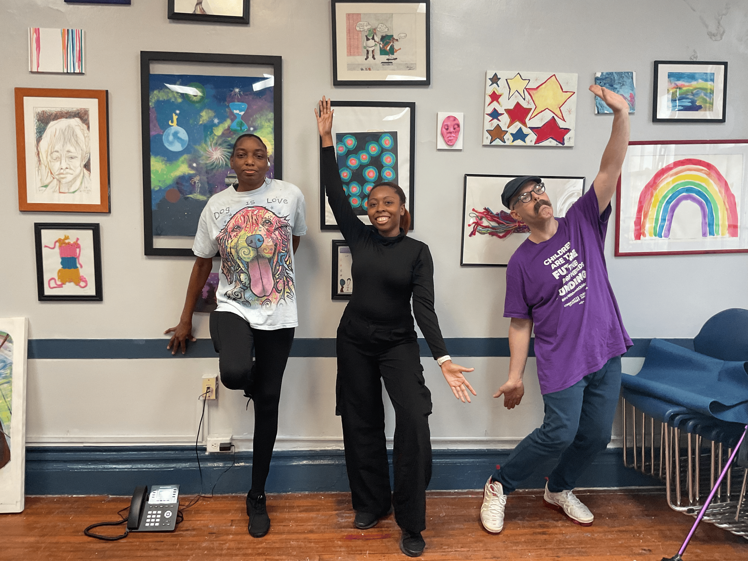 Teaching artists and participants pose in front of a community art wall during an adaptive dance and movement session. The program centers accessibility, self-expression, creativity, and inclusive arts experiences for individuals of all abilities.