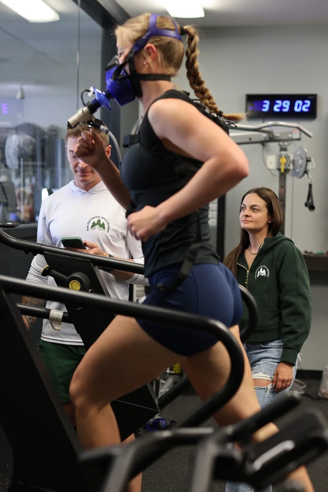 A shirtless man running on a treadmill while wearing a breathing mask connected to a machine.
