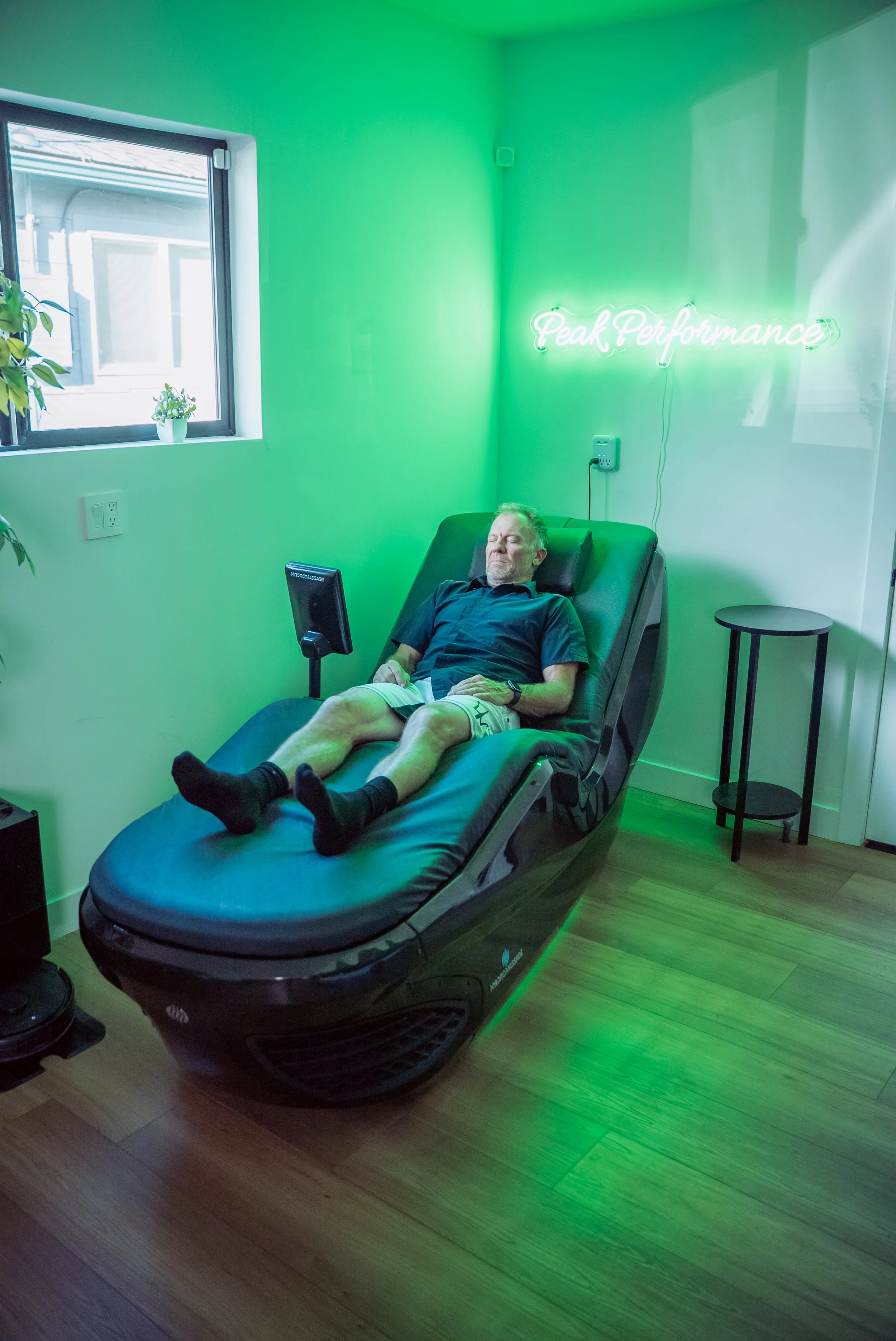 A man lying back in a futuristic chair with a computer screen mounted in front of him, in a relaxed, reclined position.