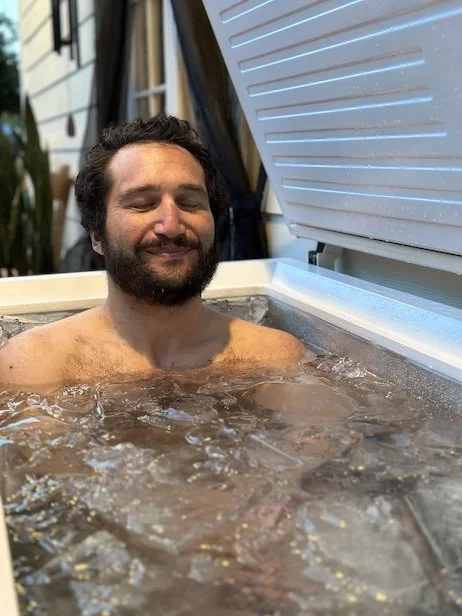 Man relaxing in an ice bath outside.