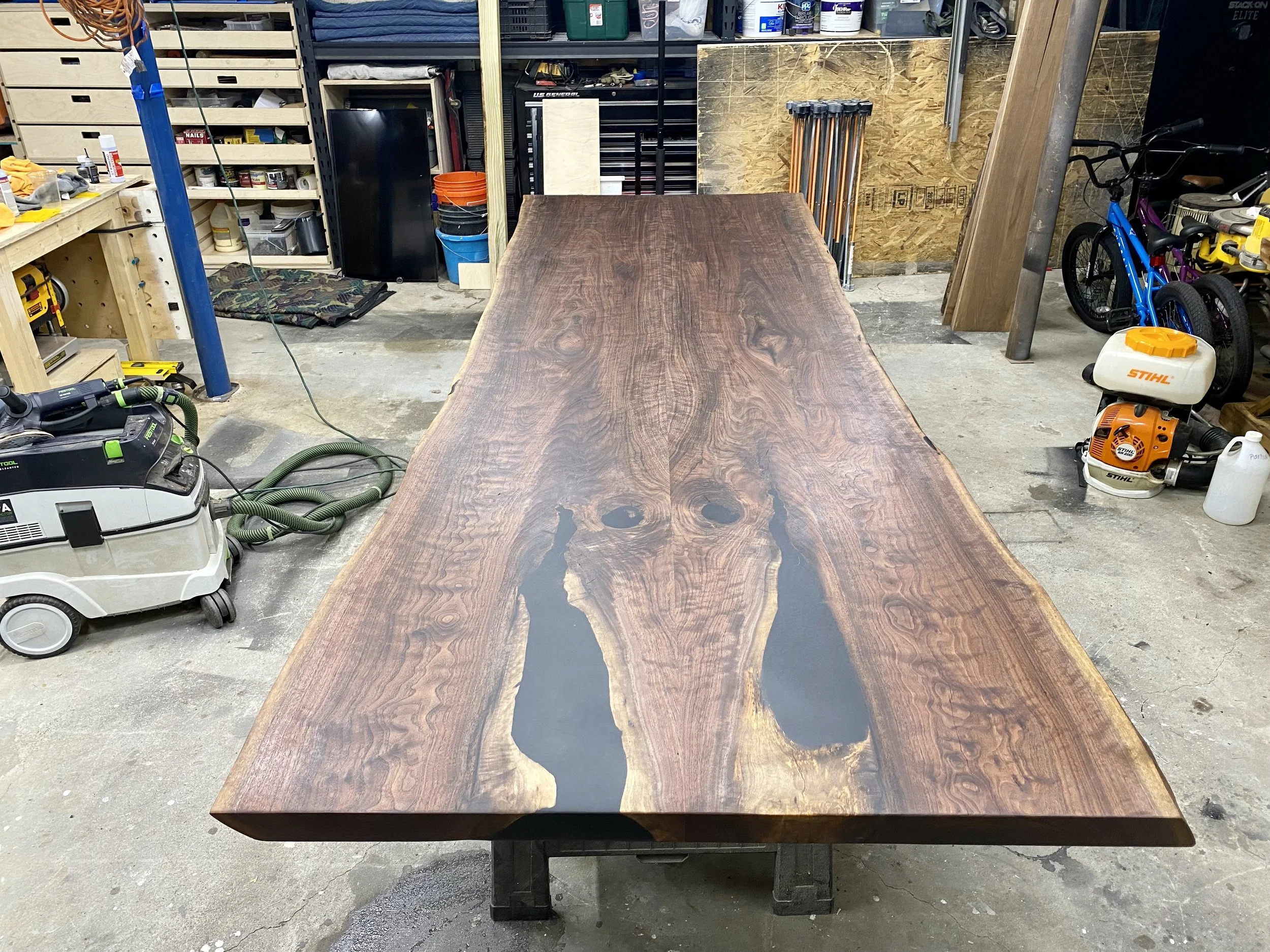 Wooden live edge table with dark and light wood tones in a workshop setting.