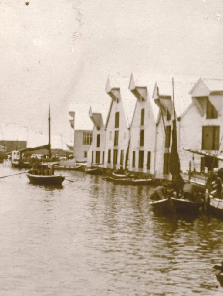 Gamle vertshus med unike tak, plassert langs en havn med båter i vannet.